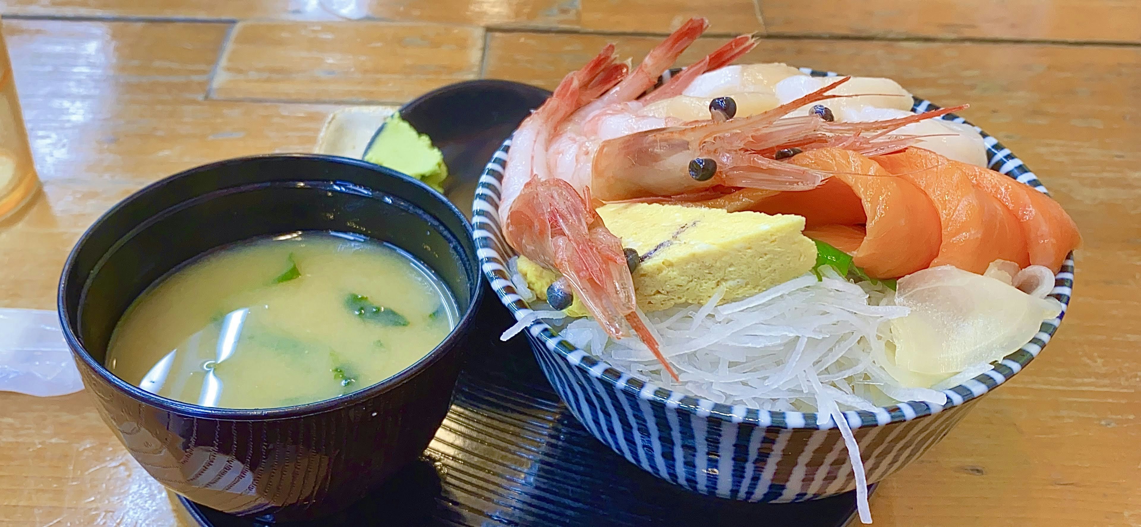 一碗海鮮飯，上面放有蝦，旁邊有一碗味噌湯