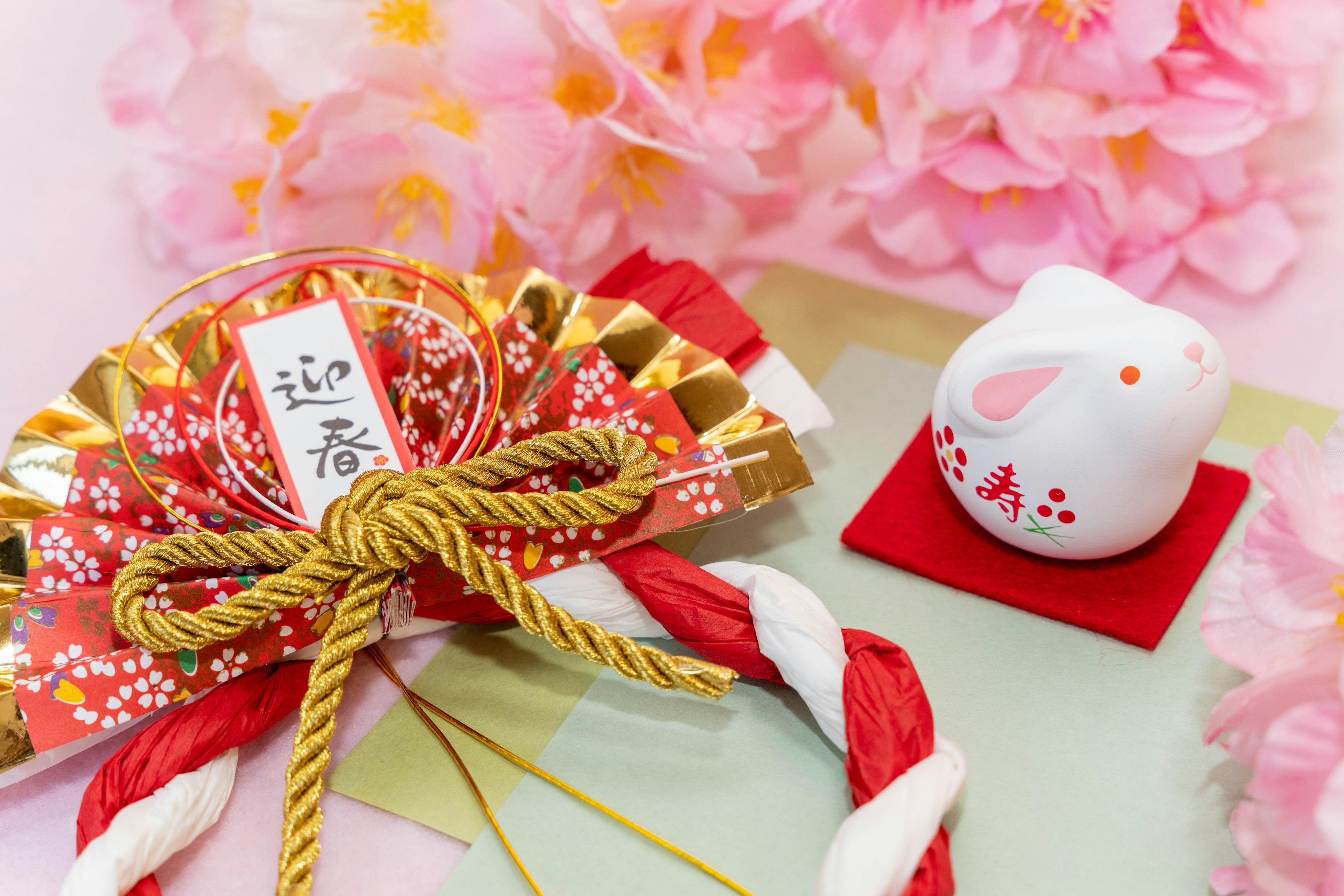 Decoración japonesa de Año Nuevo con flores coloridas, un adorno dorado y rojo y una figura de conejo blanco