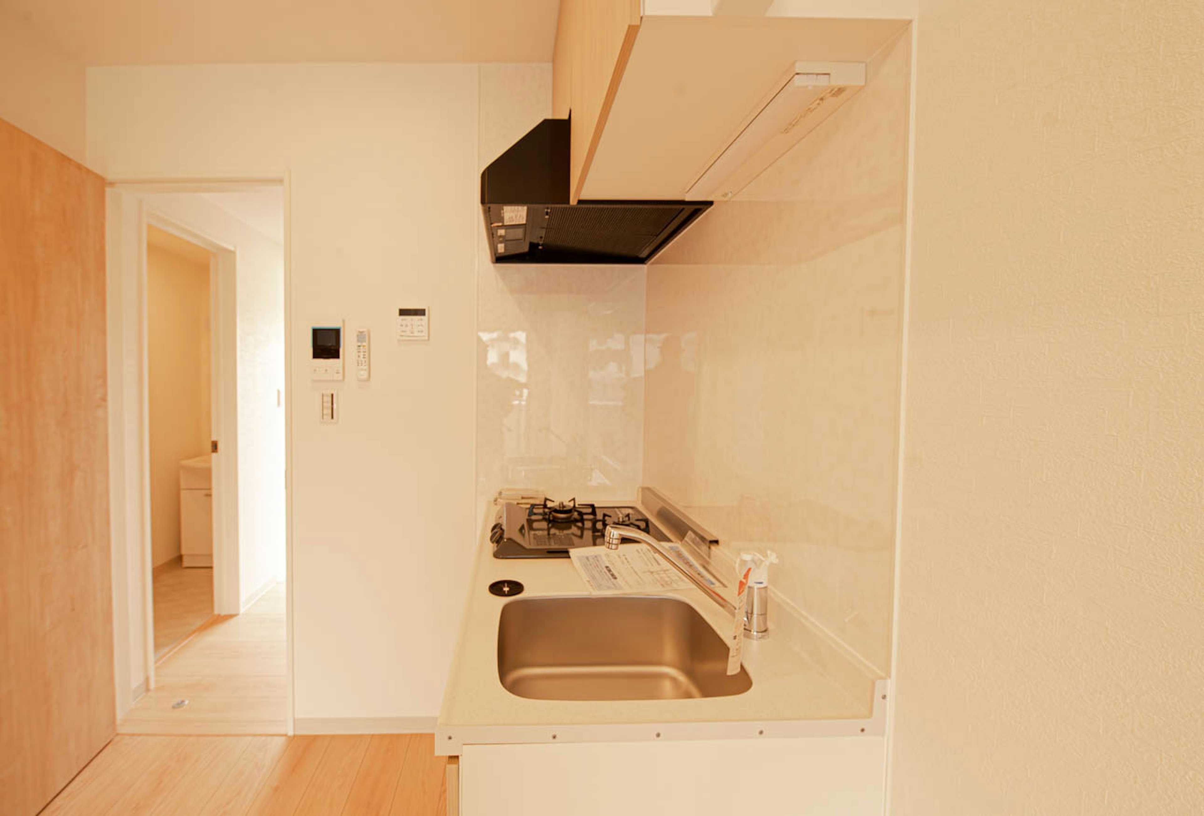 Bright and simple kitchen interior with white walls and wooden cabinets stainless steel sink and gas stove