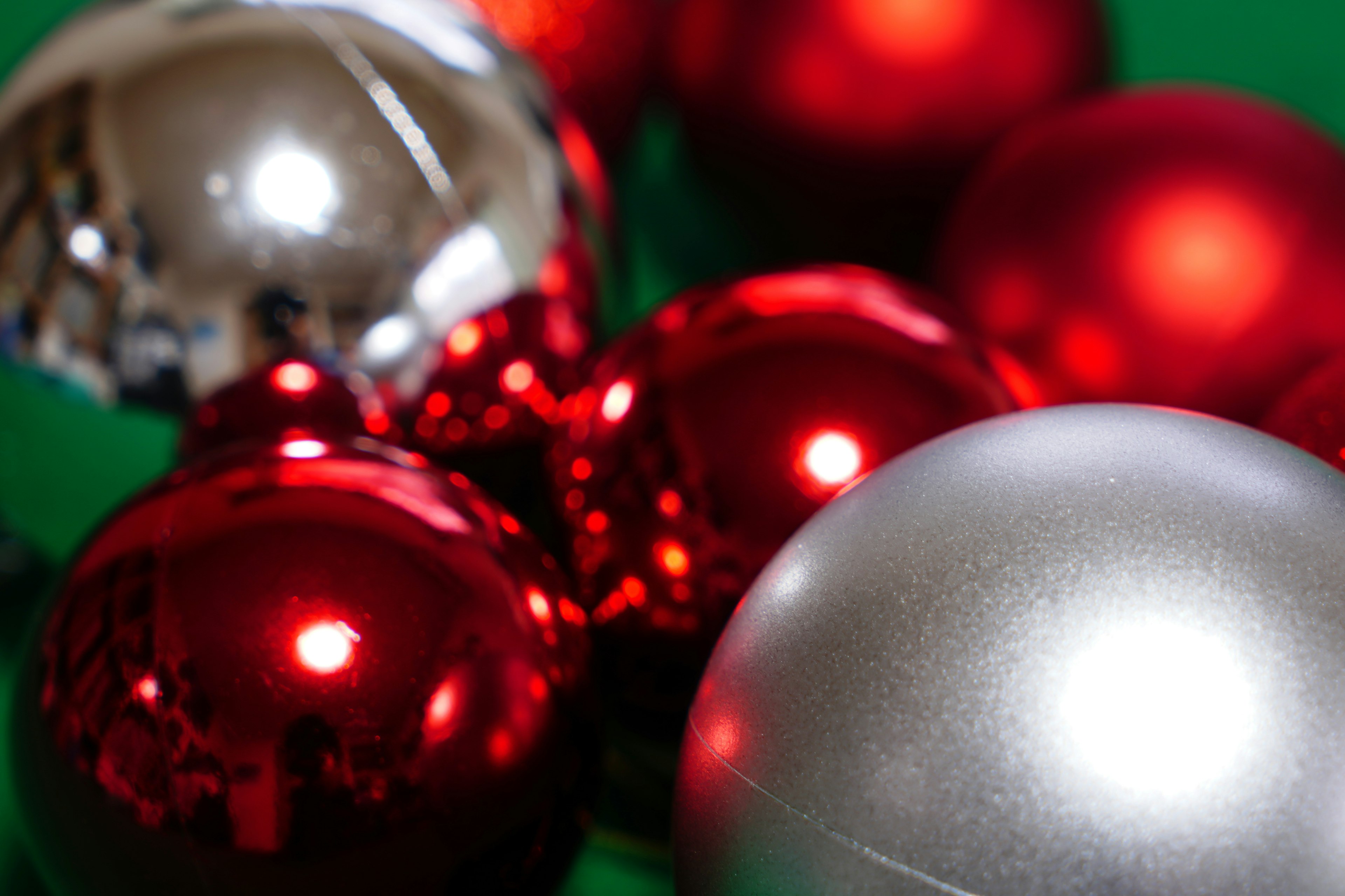 Red and silver Christmas ornaments clustered on a green background