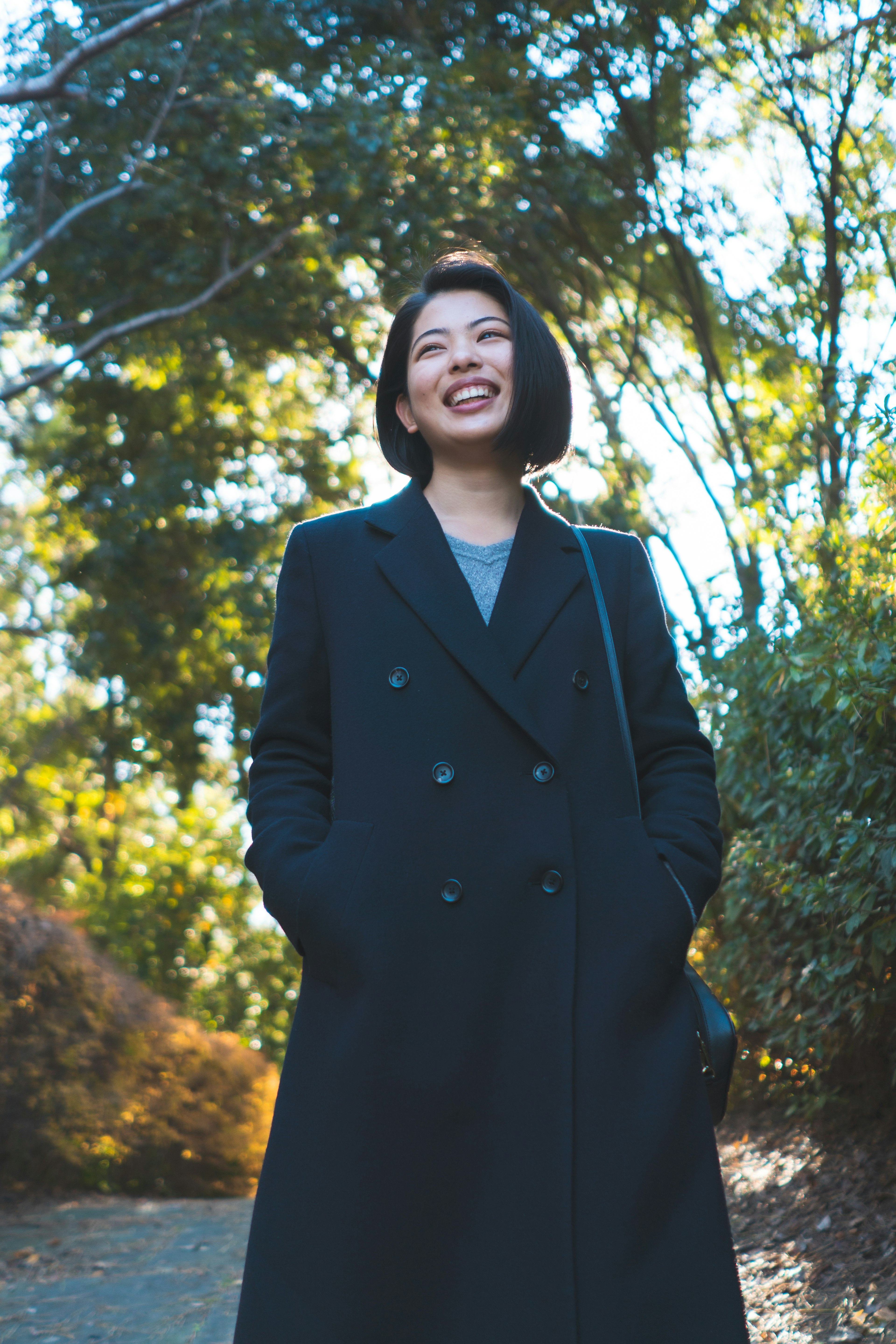 Une femme souriante en manteau noir se tenant dans un fond vert