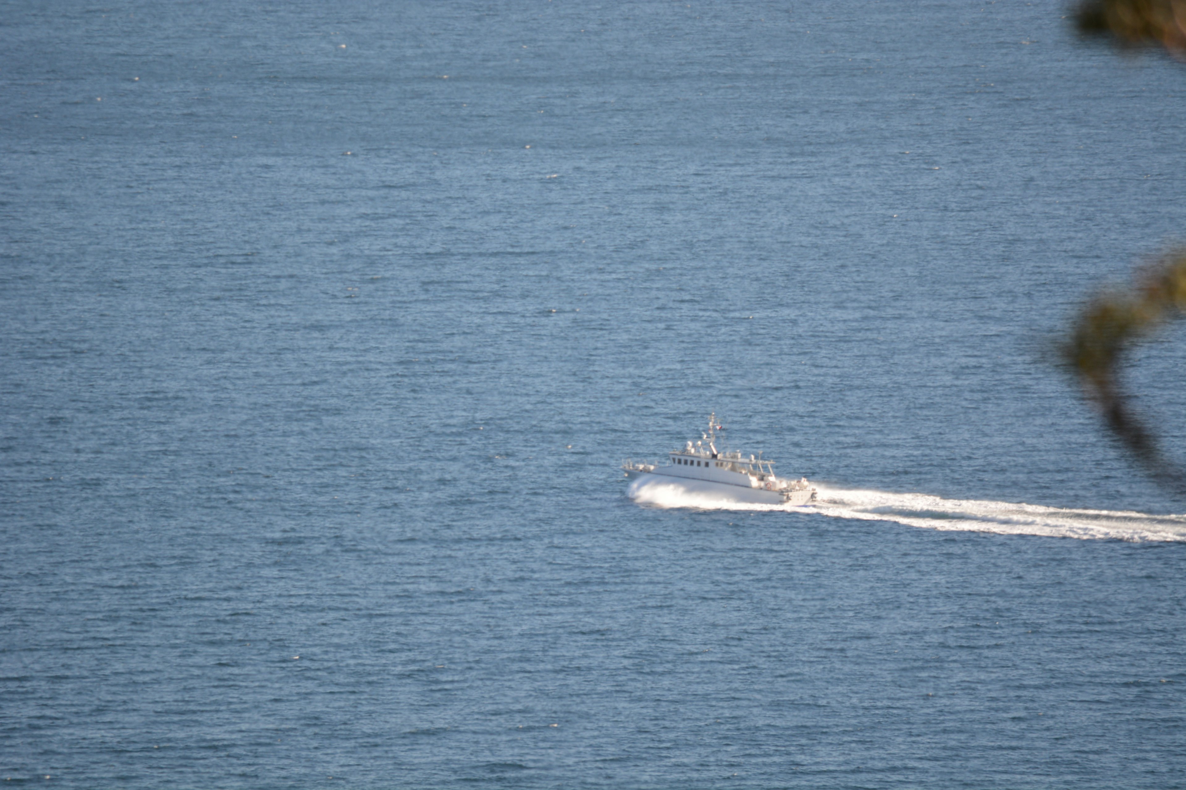 Boat gliding over a blue lake surface with trailing waves