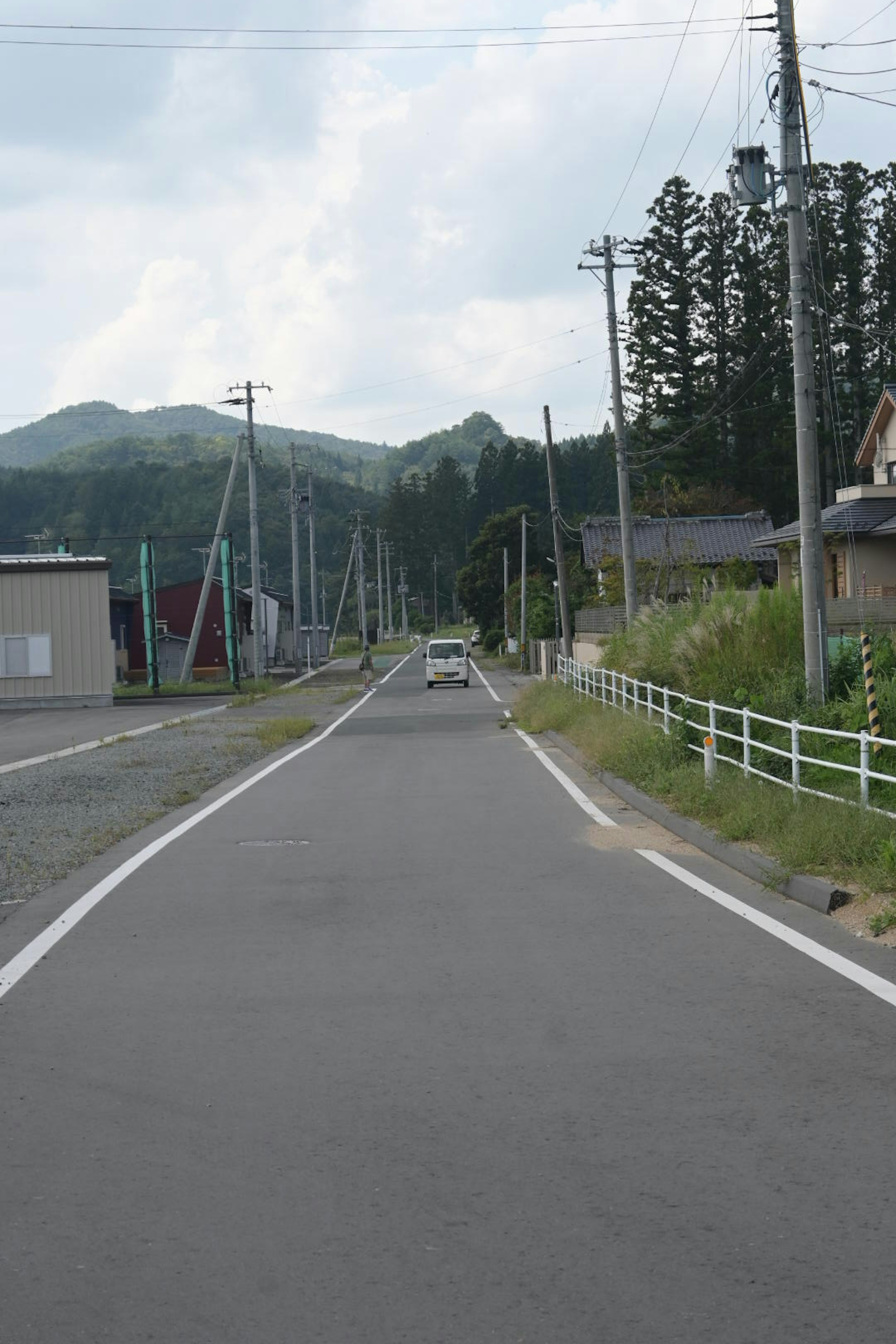 Quiet rural road with houses and mountains in the background