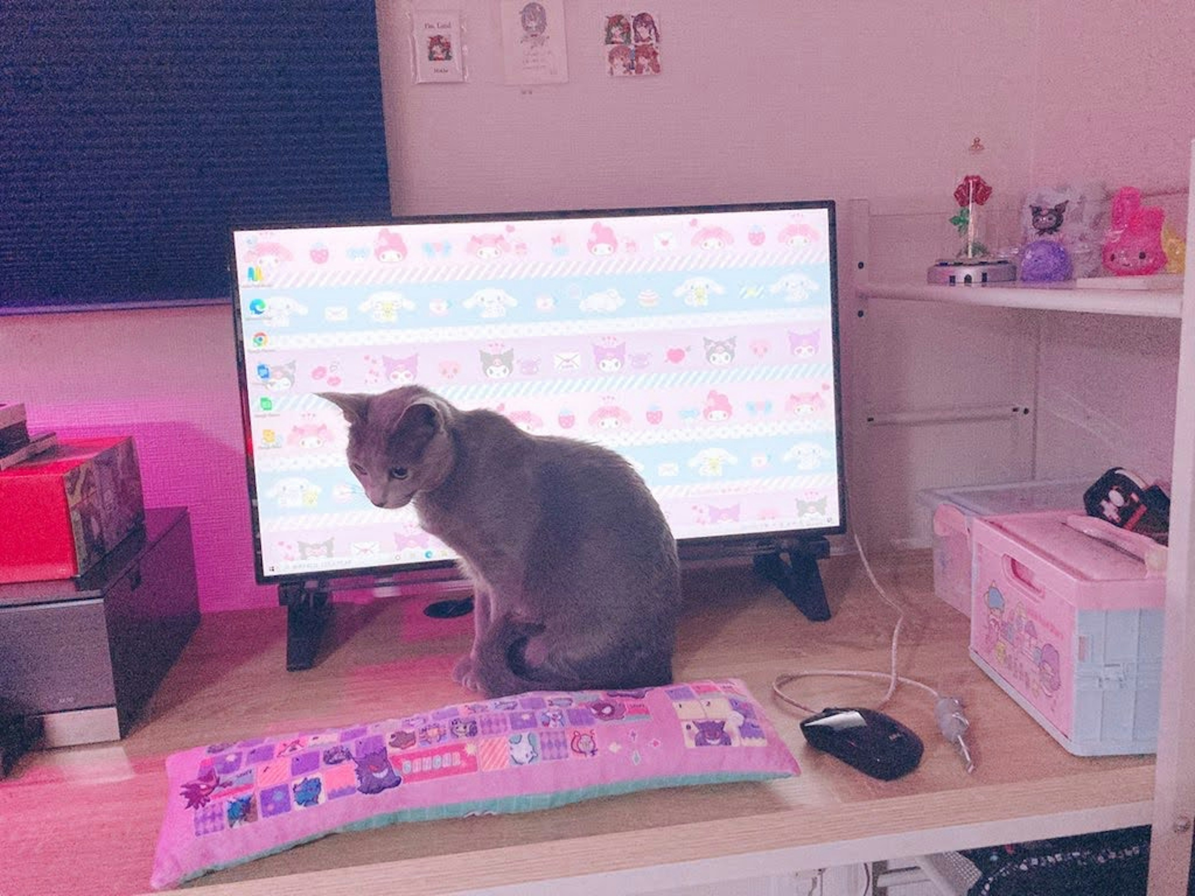 A cat sitting on top of a television in a room with a desk