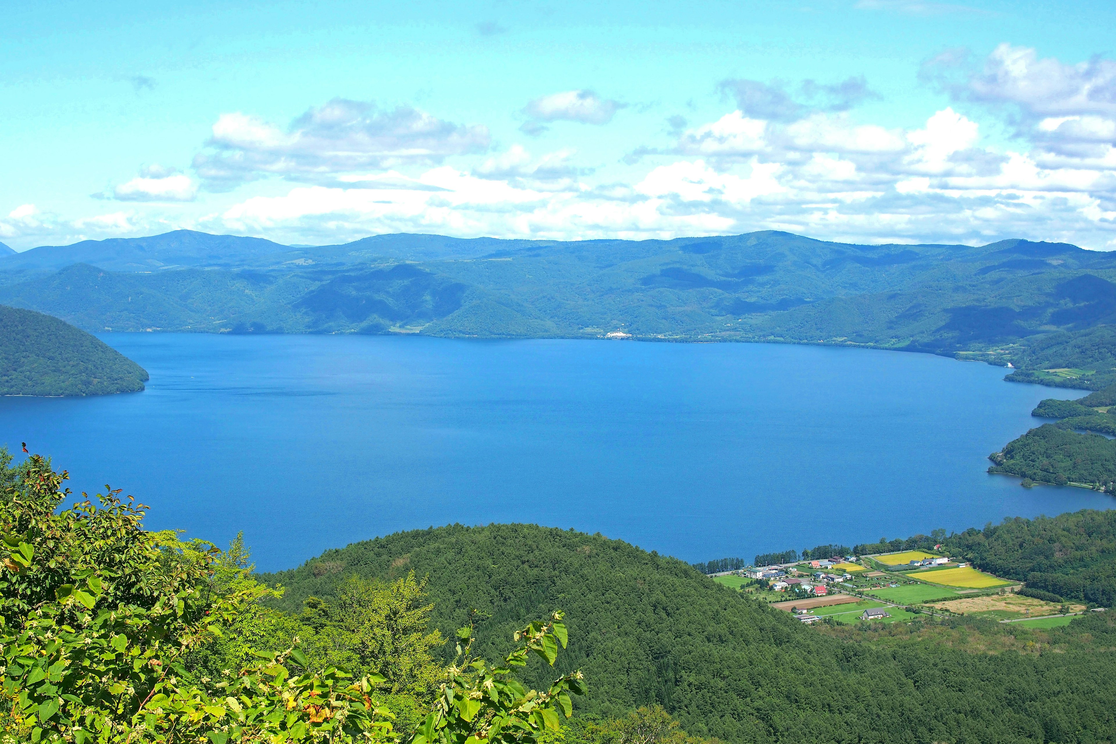 Pemandangan indah dengan danau biru dikelilingi gunung hijau