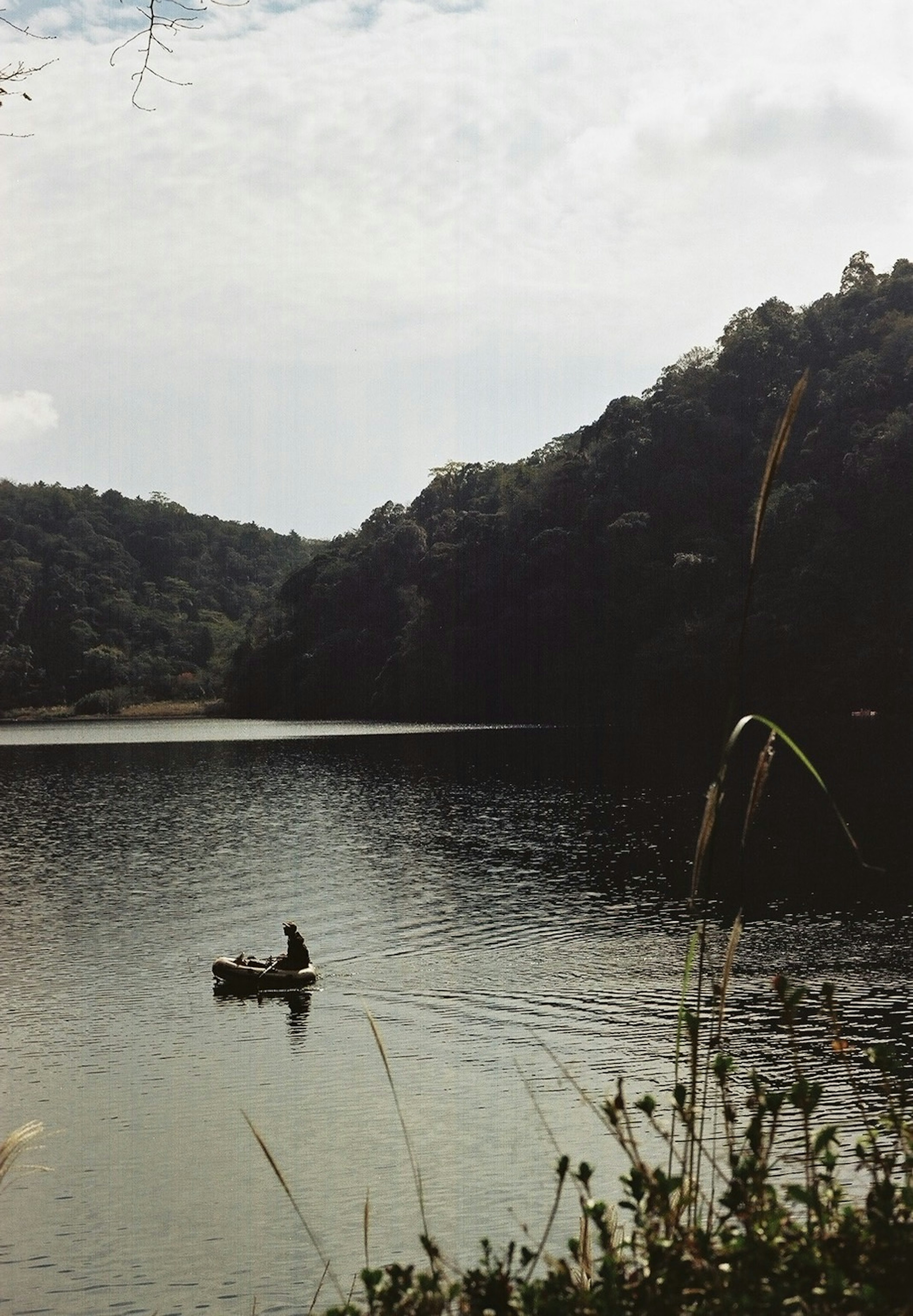 A person paddling a canoe on a lake surrounded by nature