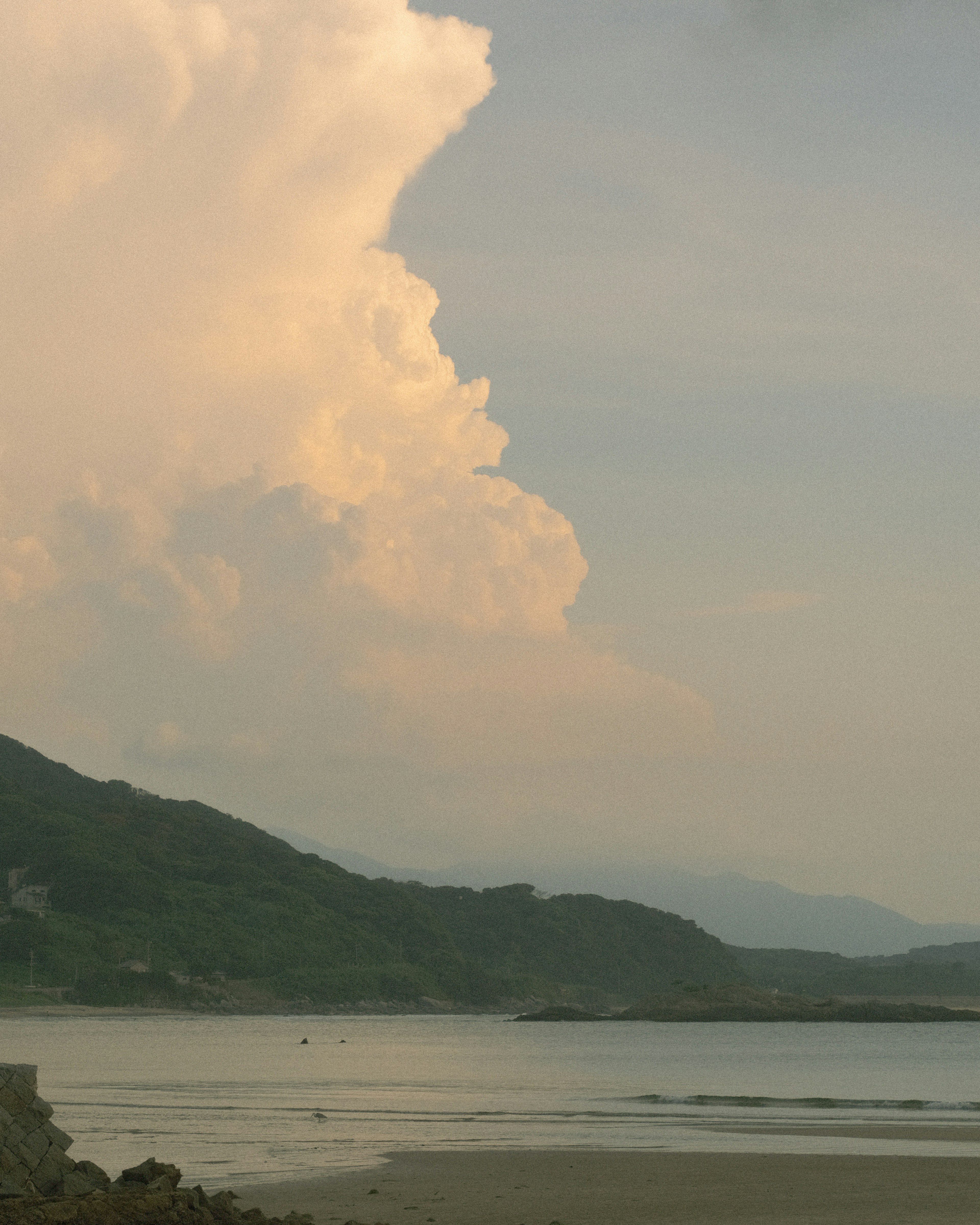 穏やかな海と山の風景に浮かぶ大きな雲