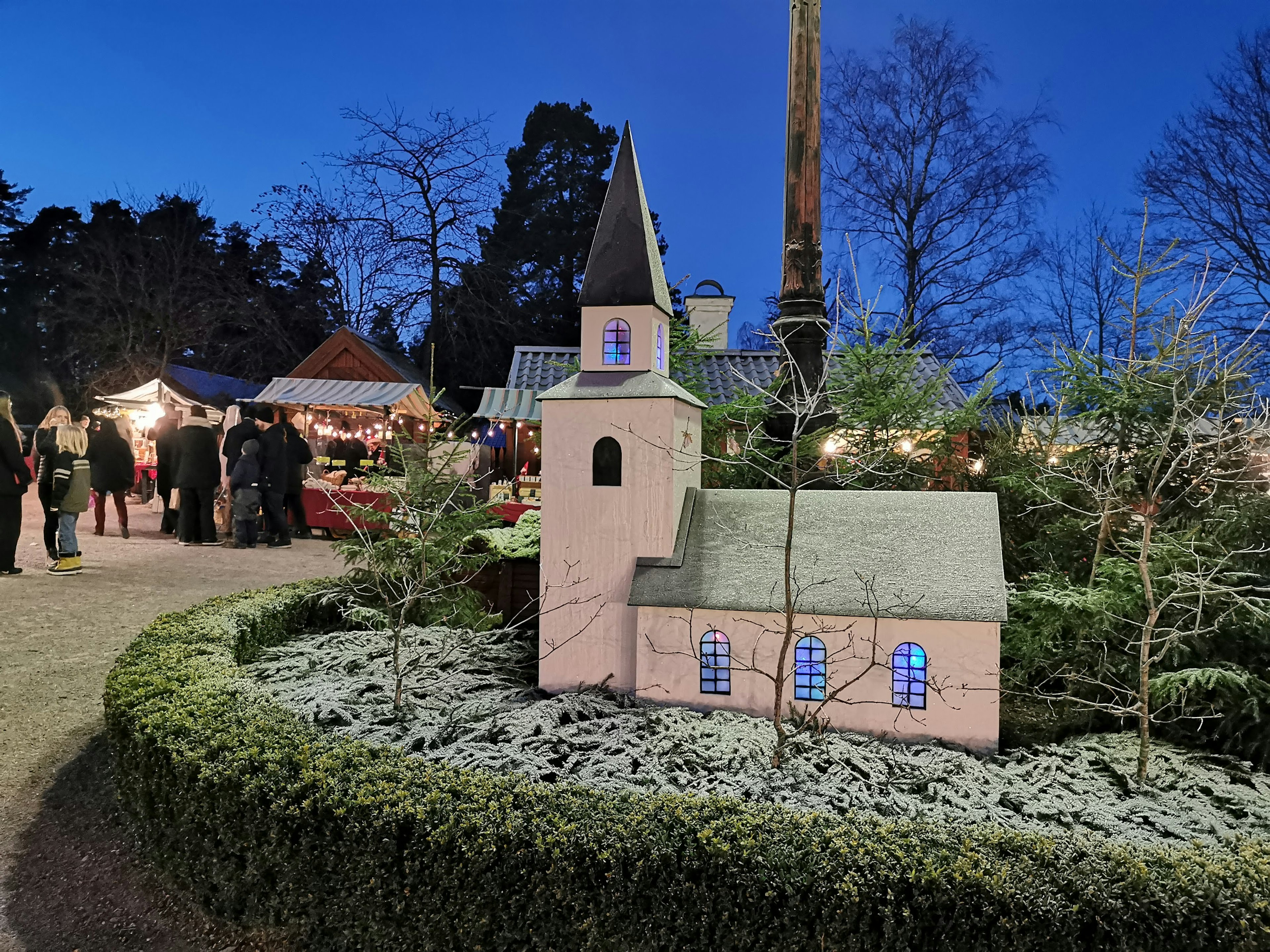 Small illuminated church surrounded by greenery during winter evening