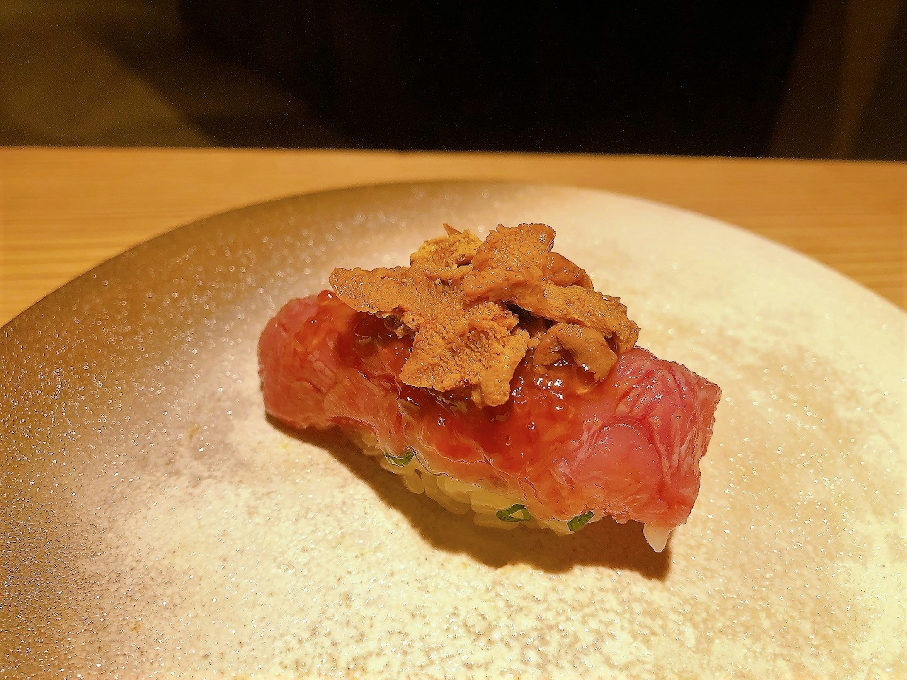 A beautiful sushi piece topped with red fish and sea urchin