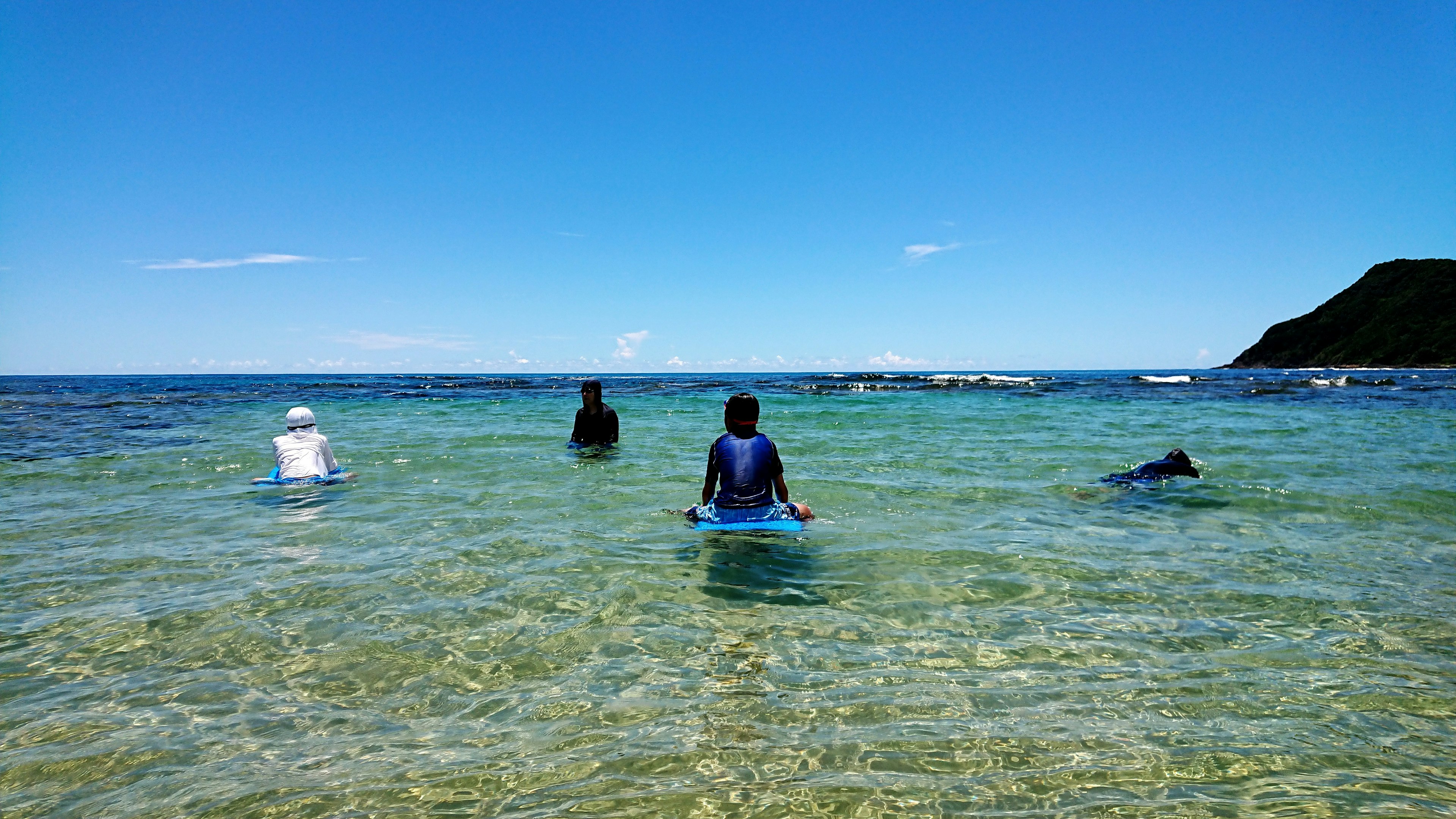 Persone che camminano in acqua blu e chiara in una giornata di sole