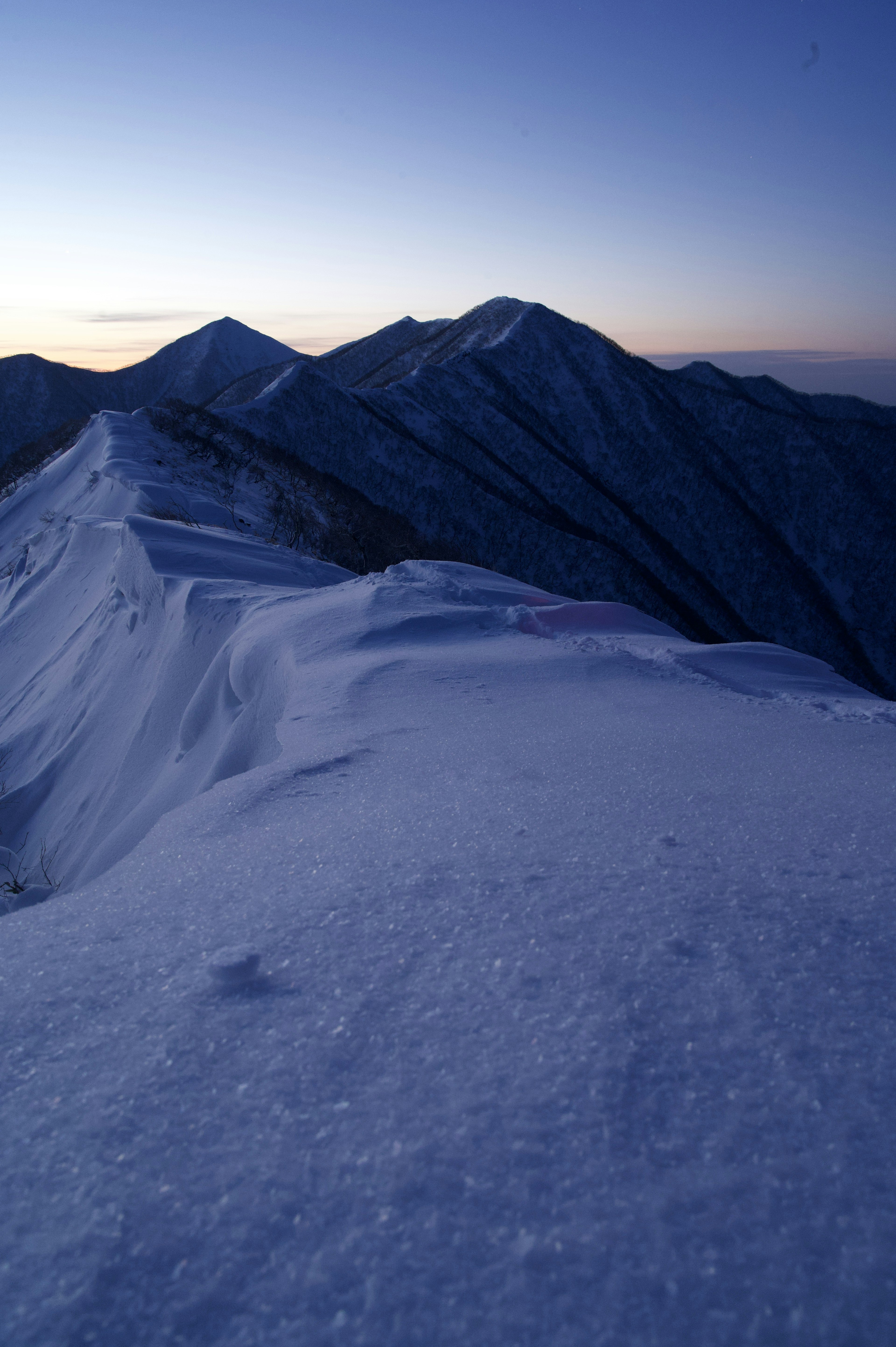 Cumbres montañosas cubiertas de nieve bajo un cielo crepuscular