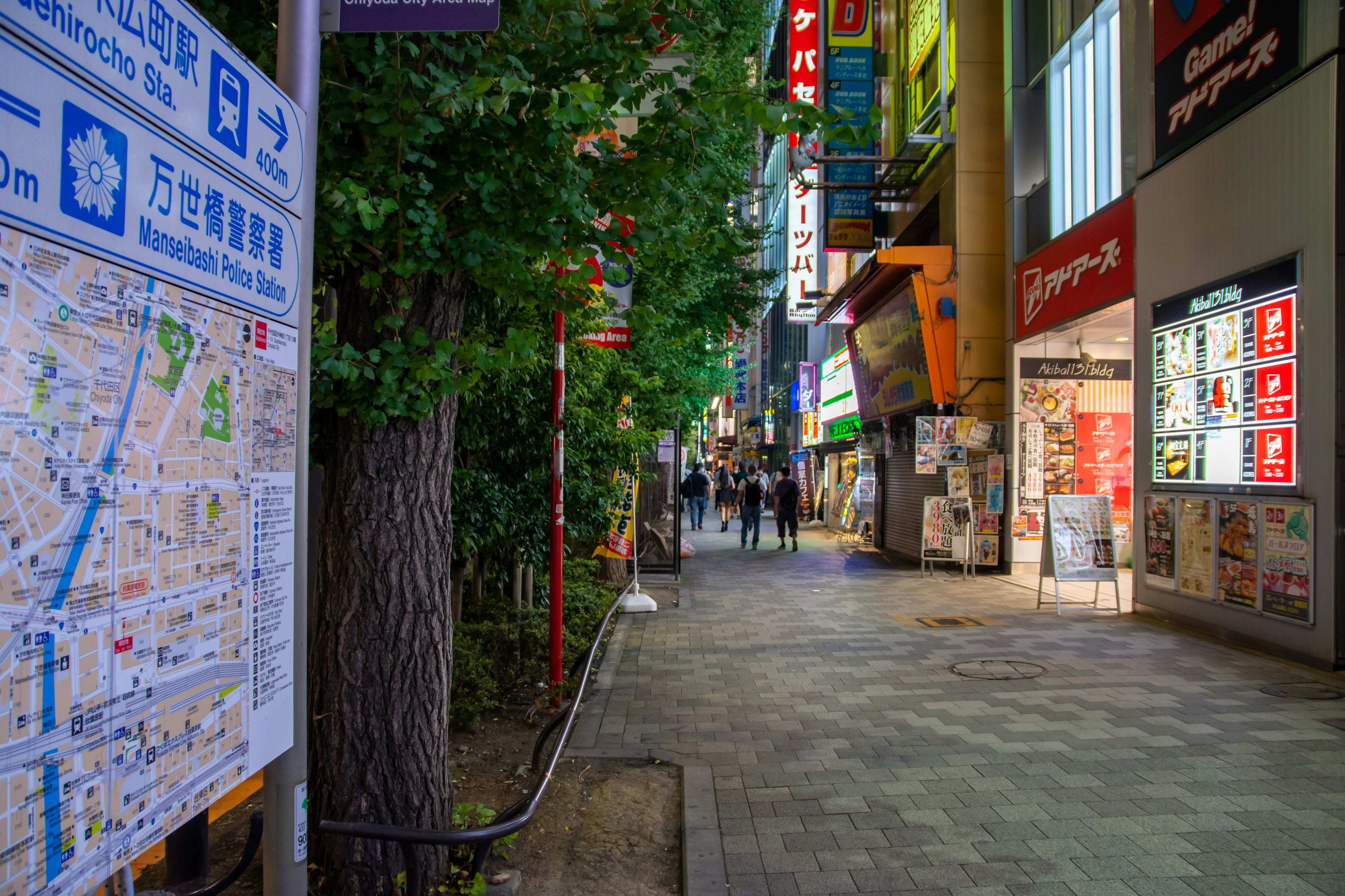 Night view of a bustling street people walking with a map sign and store lights