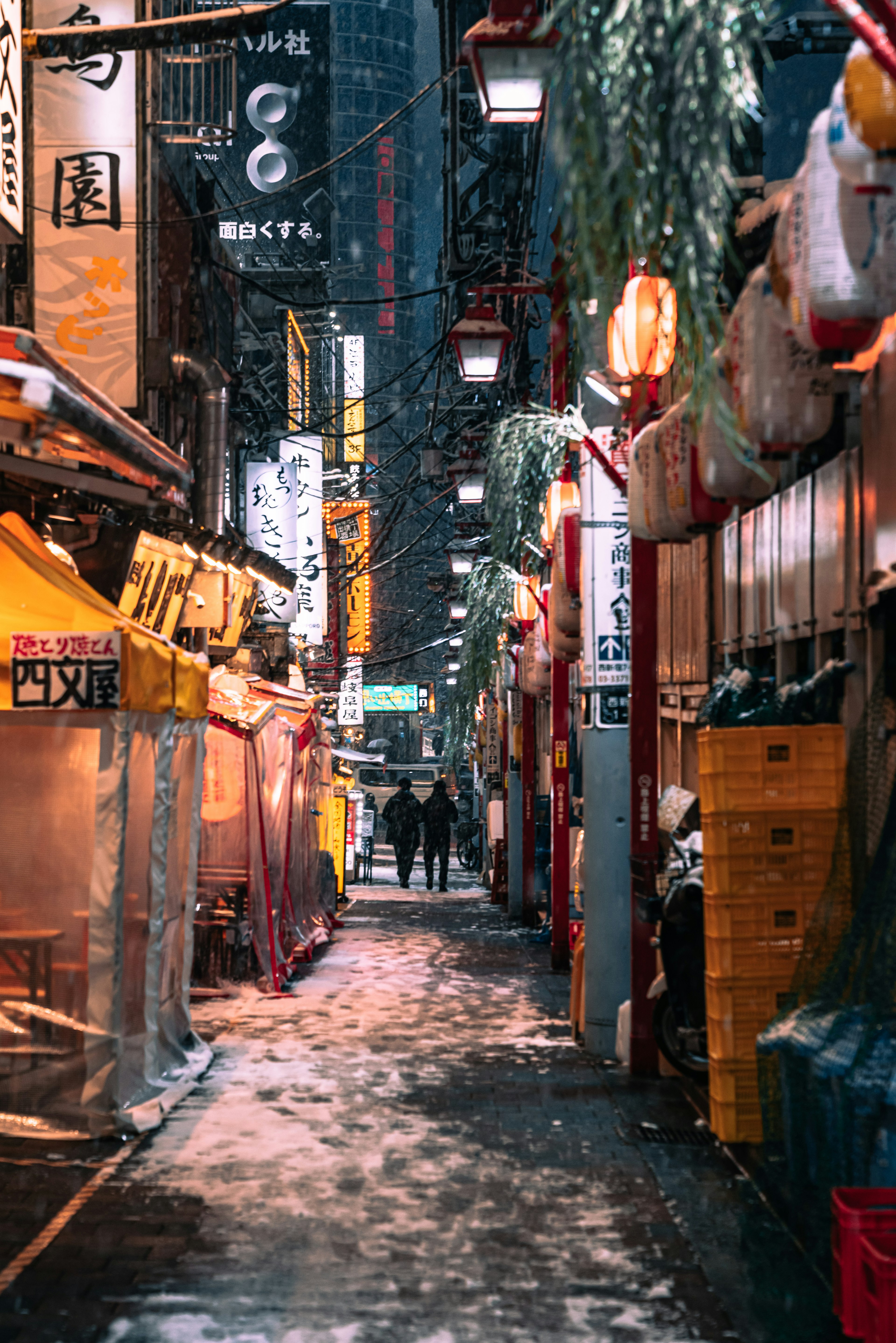 Calle estrecha en Tokio de noche con nieve múltiples letreros de restaurantes y faroles