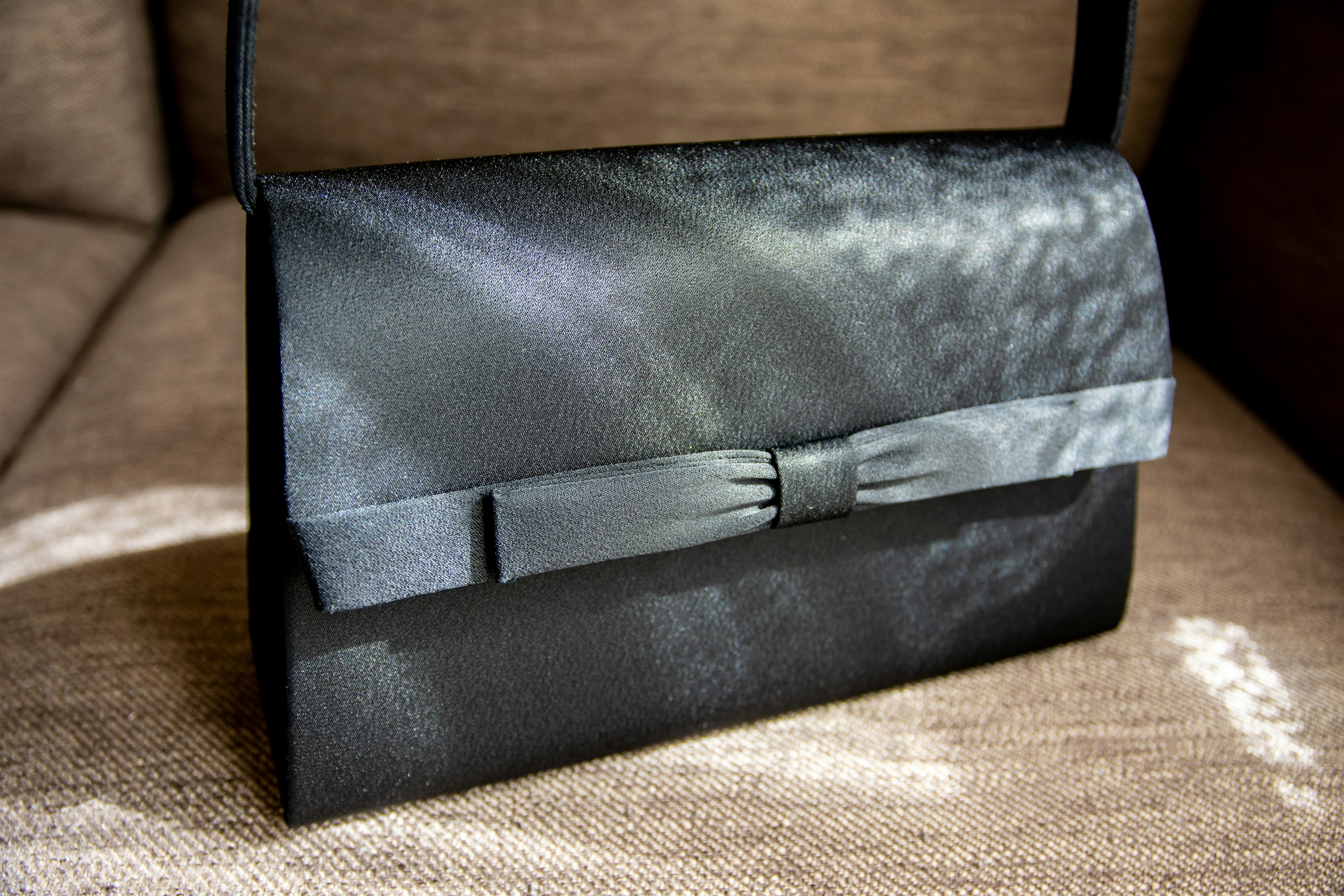 Black satin handbag featuring a ribbon decoration