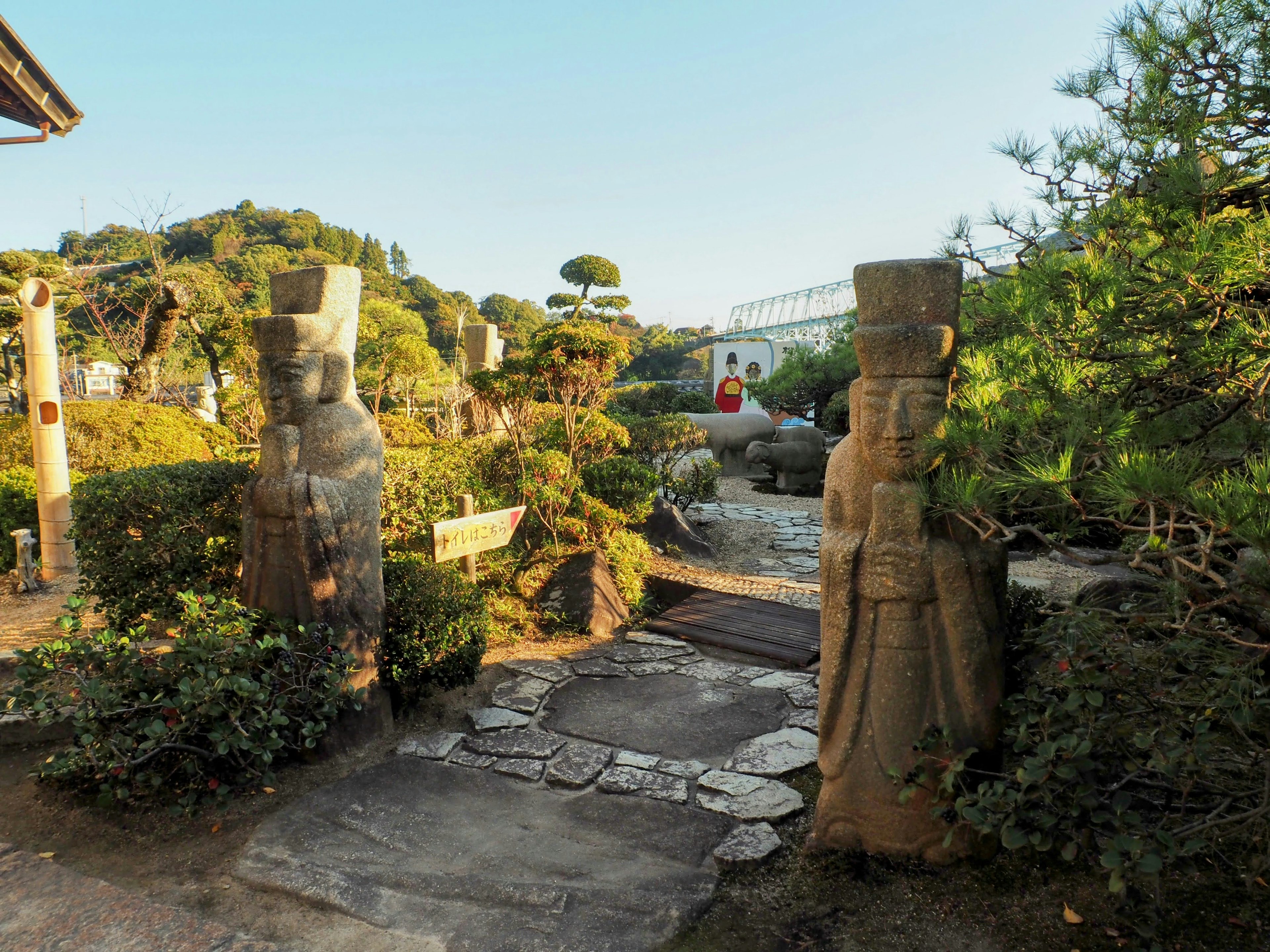 Vue d'un jardin avec des statues en pierre végétation luxuriante et un chemin en pierre