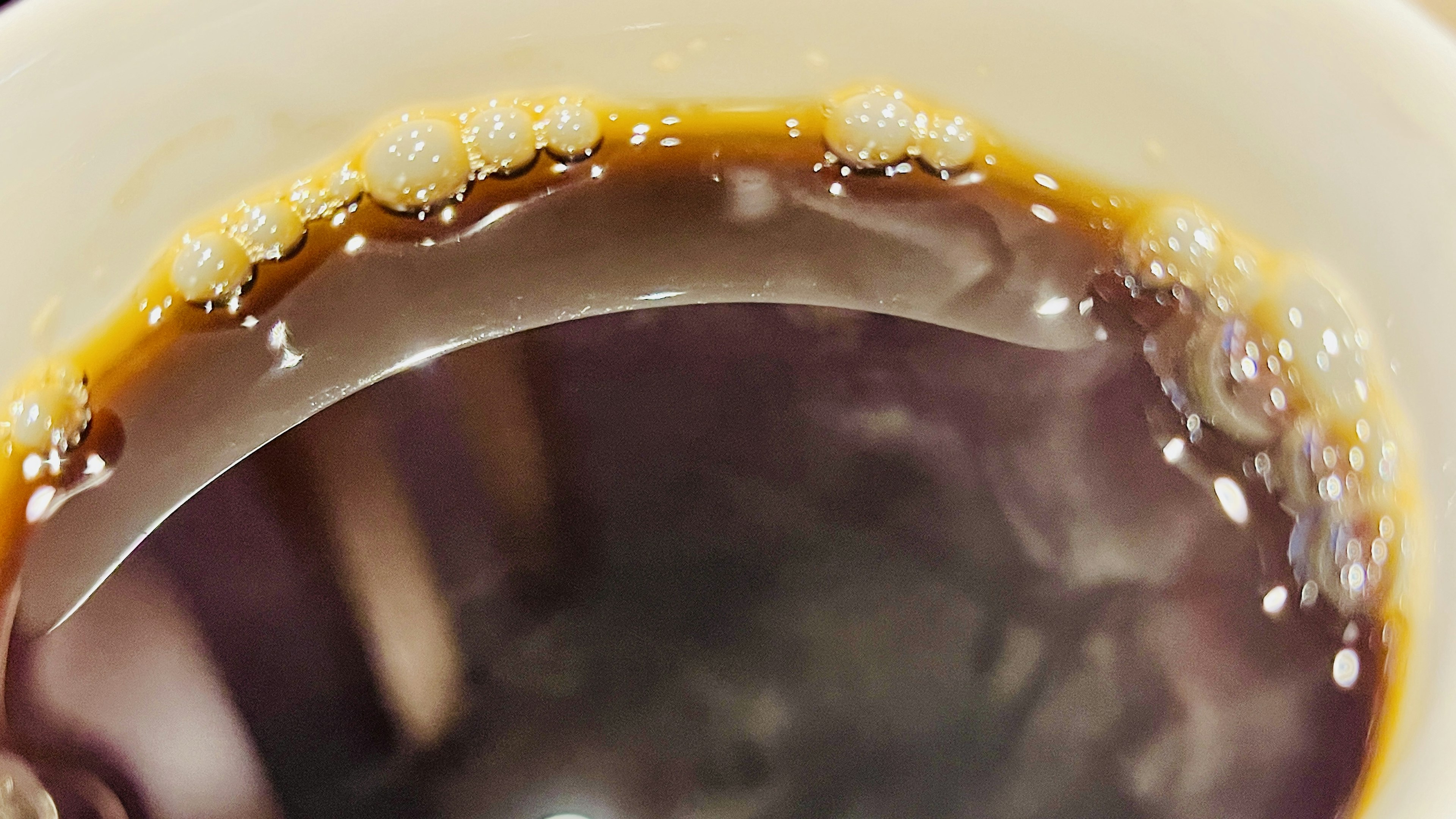 Close-up of dark coffee surface with foam inside a cup