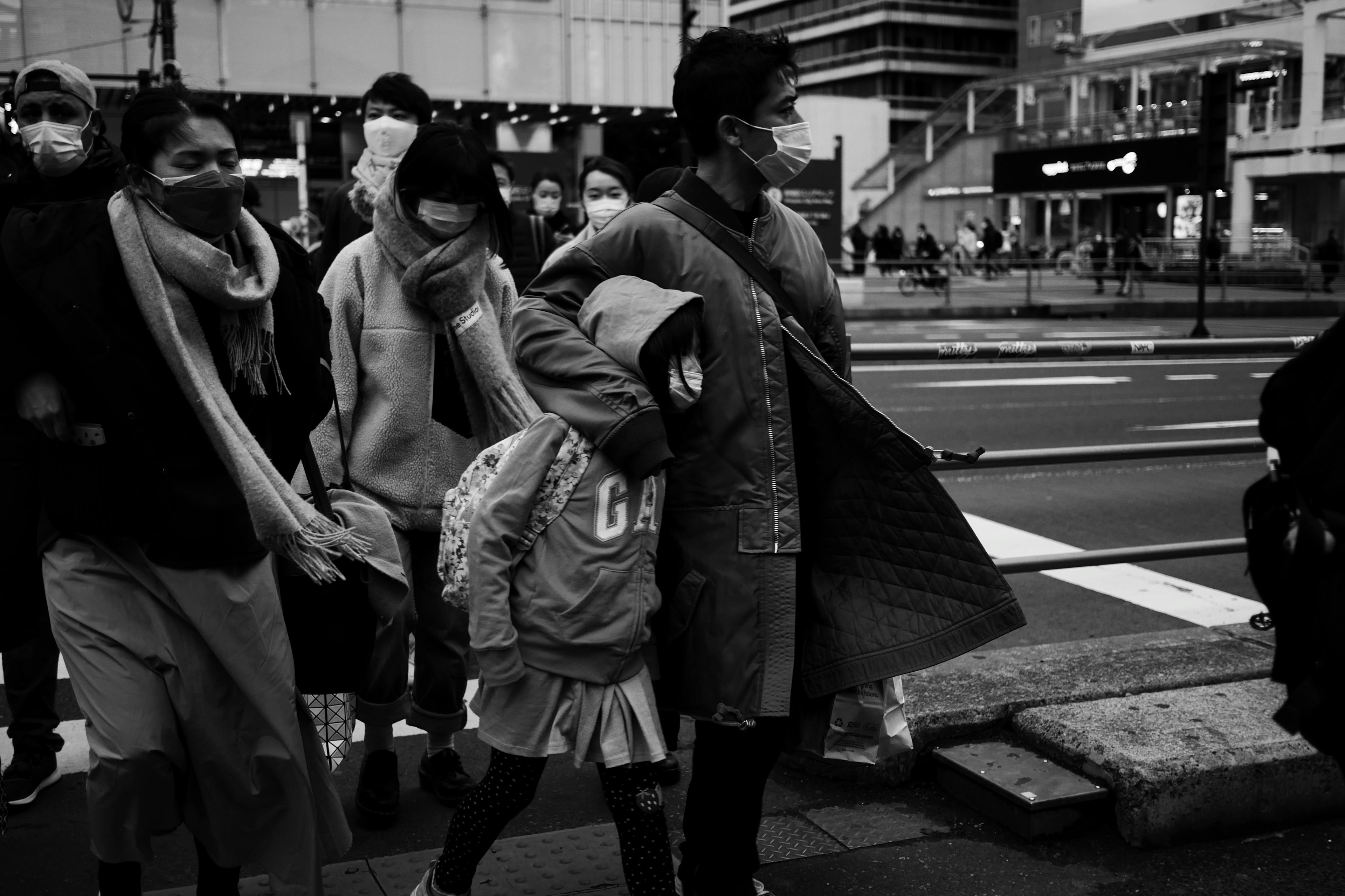 Image en noir et blanc de personnes masquées traversant une rue