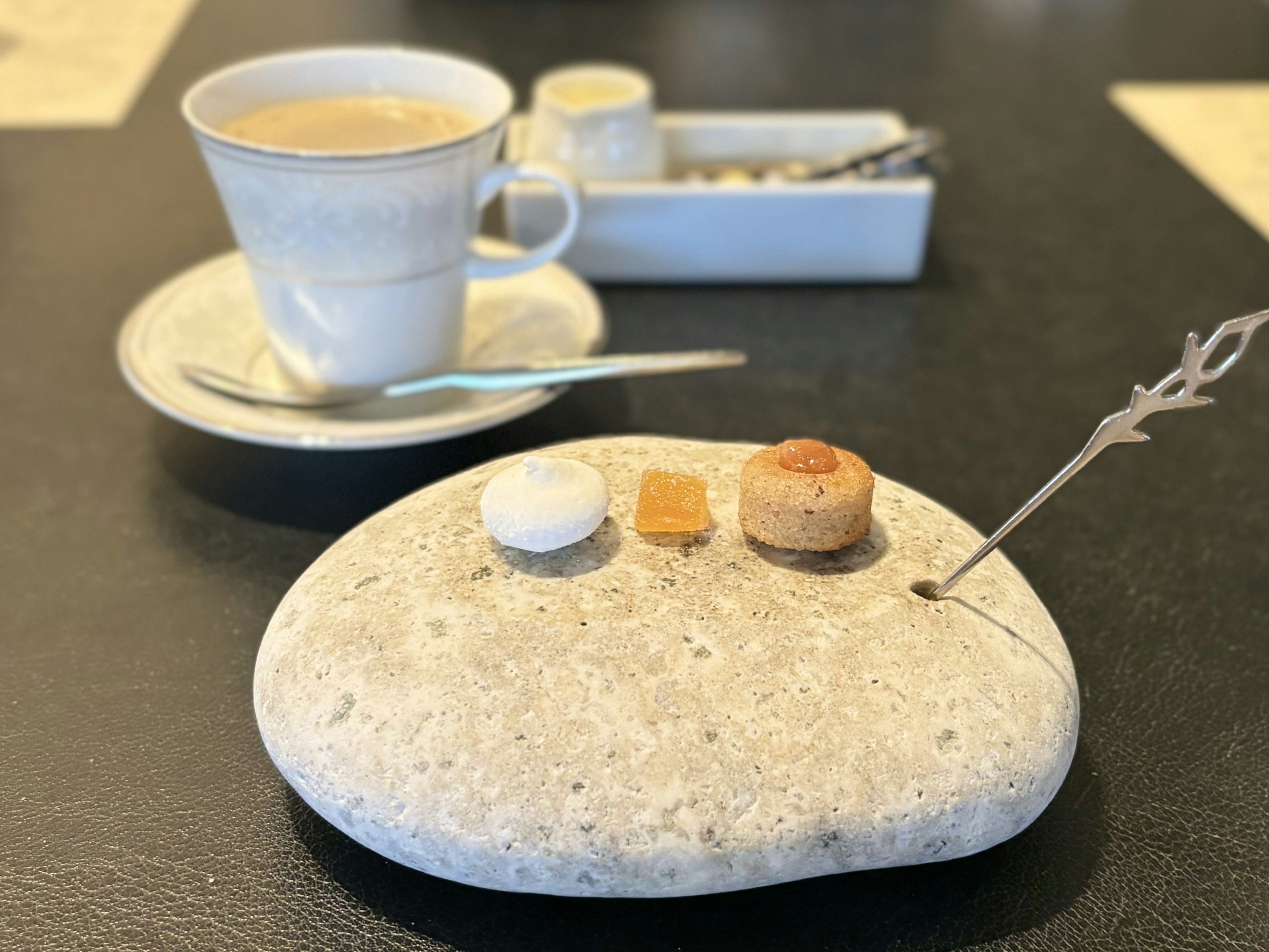 Une assiette en pierre avec des bonbons à côté d'une tasse de café