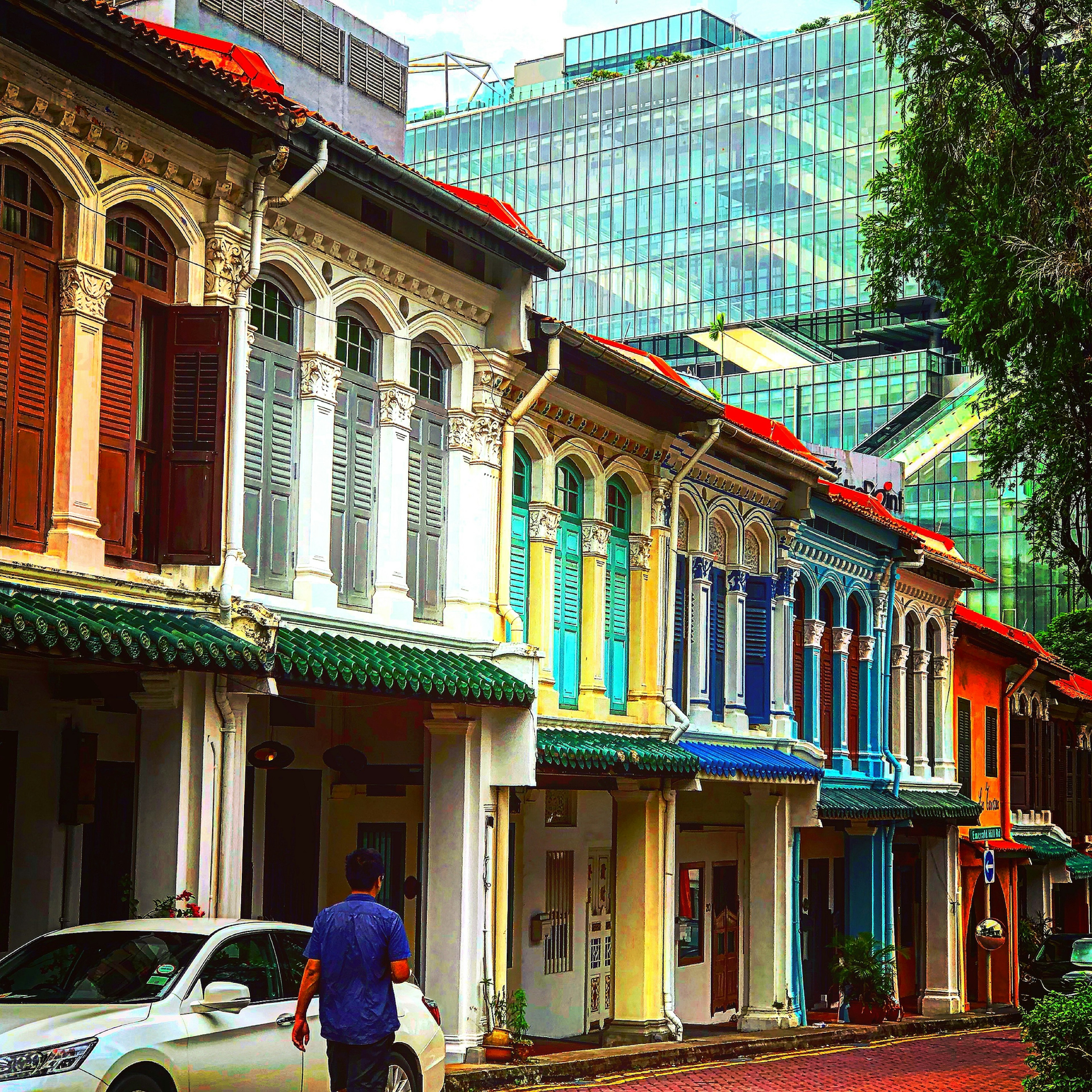 Colorful shophouses lining the street with modern buildings in the background