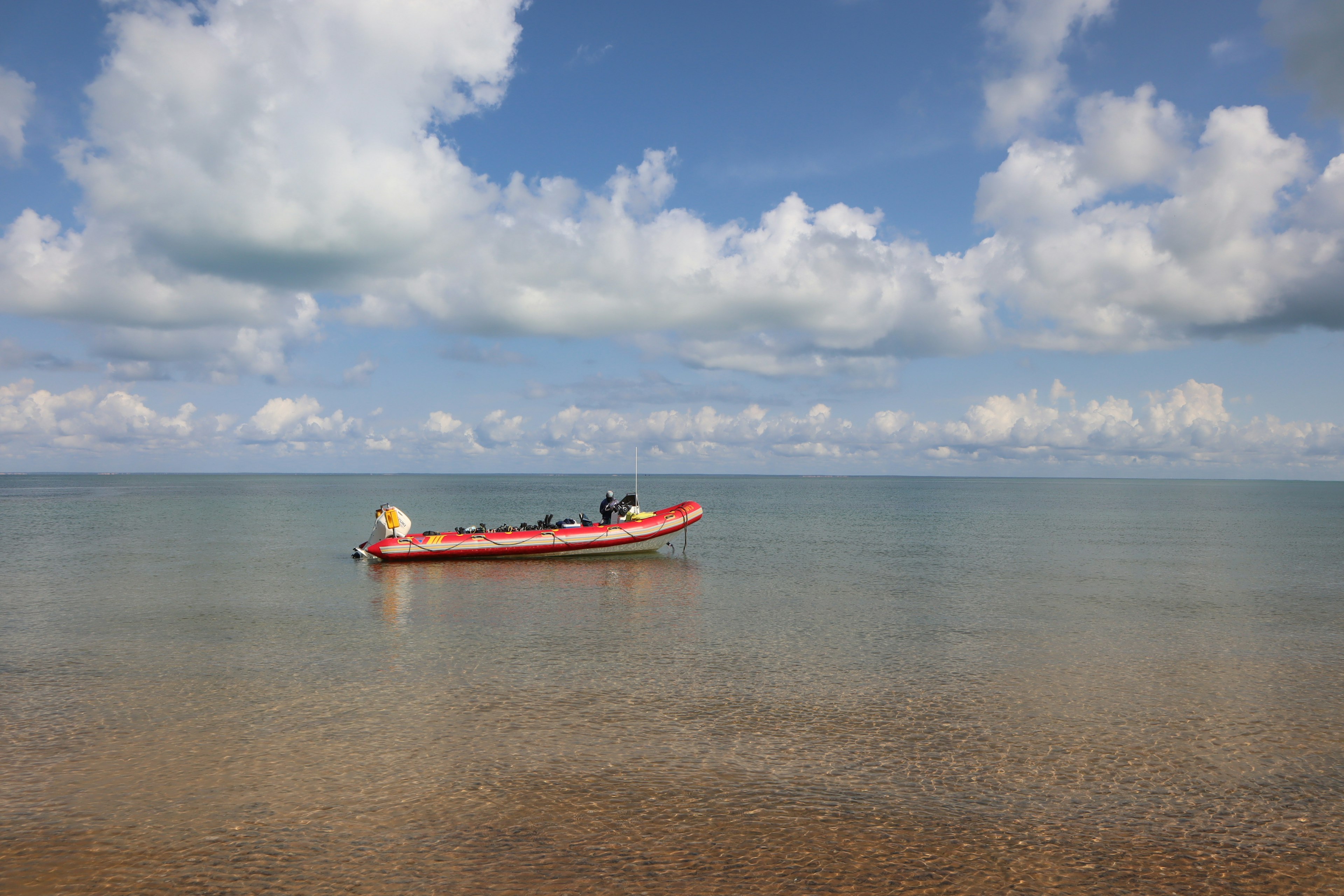 Un bateau rouge flottant sur des eaux calmes sous un ciel bleu