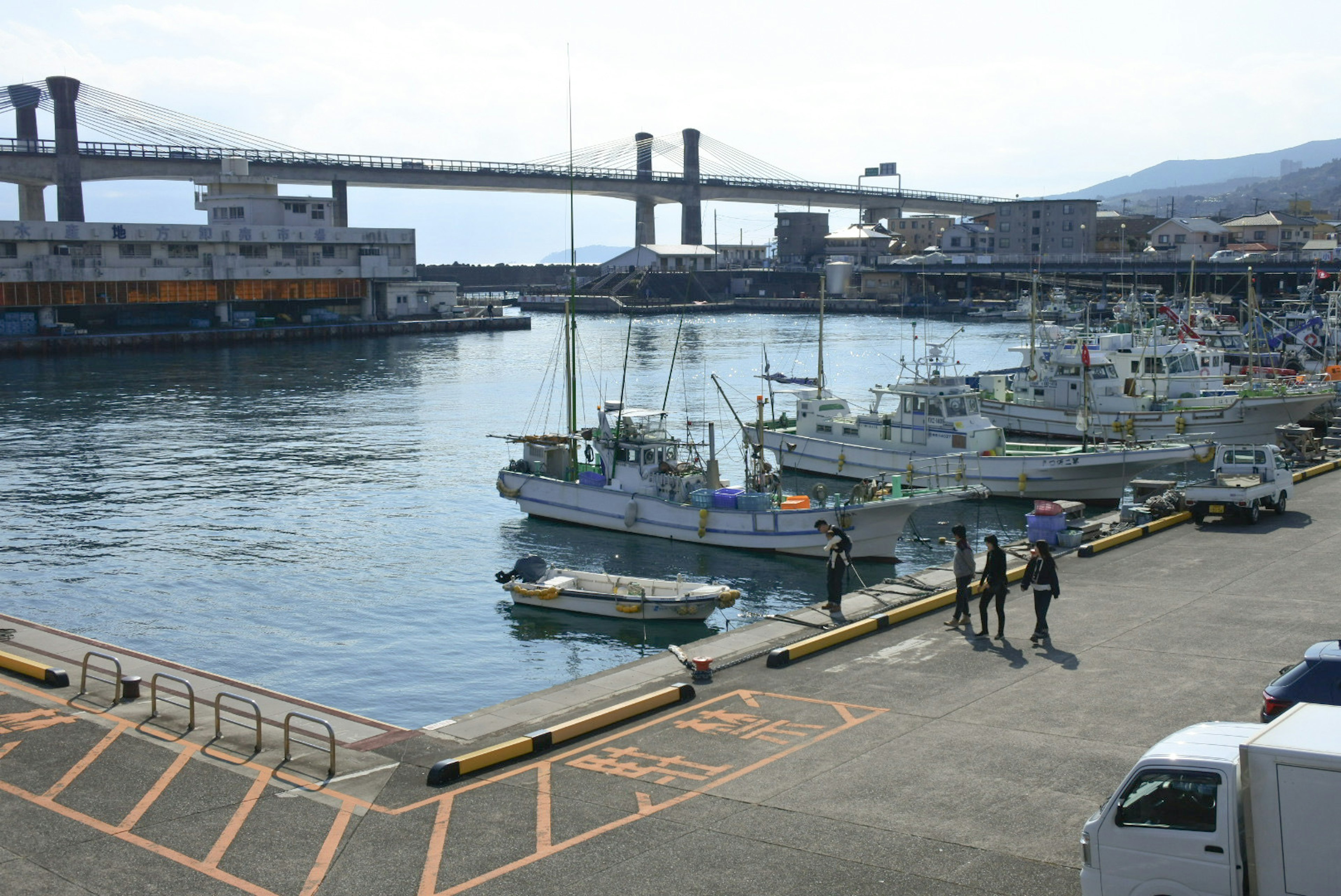 Vista escénica de botes de pesca atracados en el puerto con personas caminando