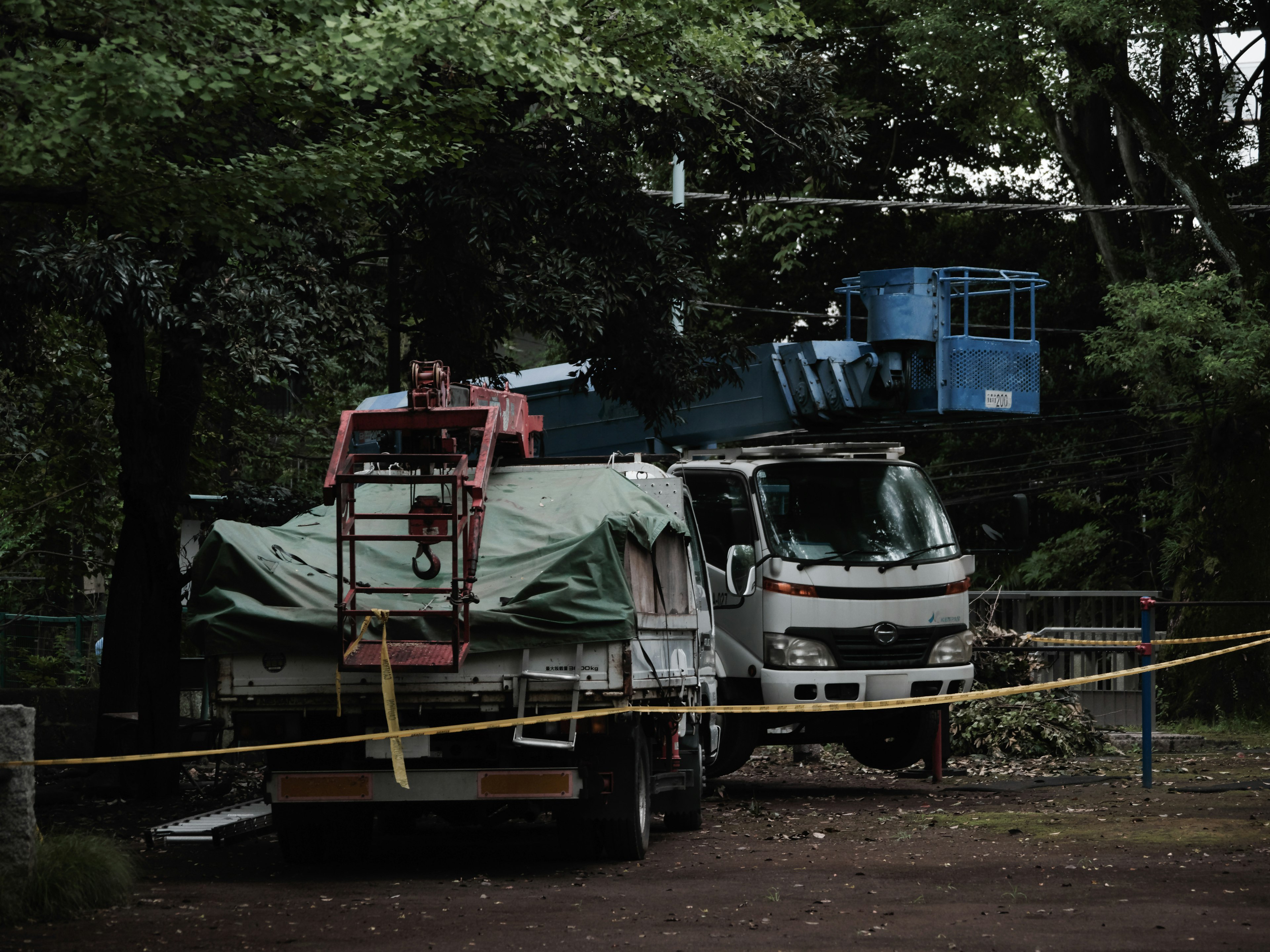 Großer Lastwagen und Arbeitsfahrzeug geparkt, umgeben von grünen Bäumen