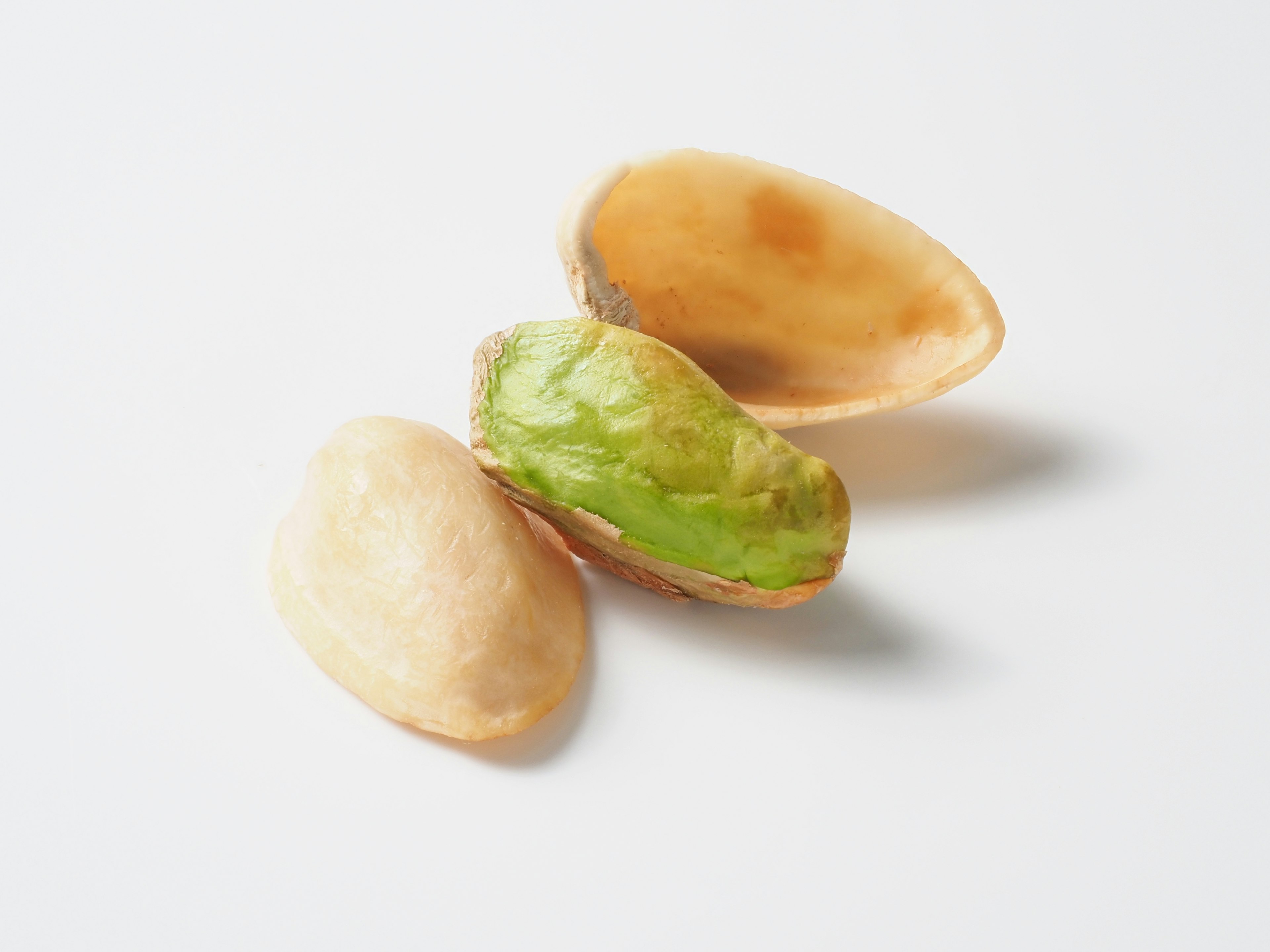 Kacang pistachio hijau dengan cangkangnya dan cangkang kosong di sampingnya