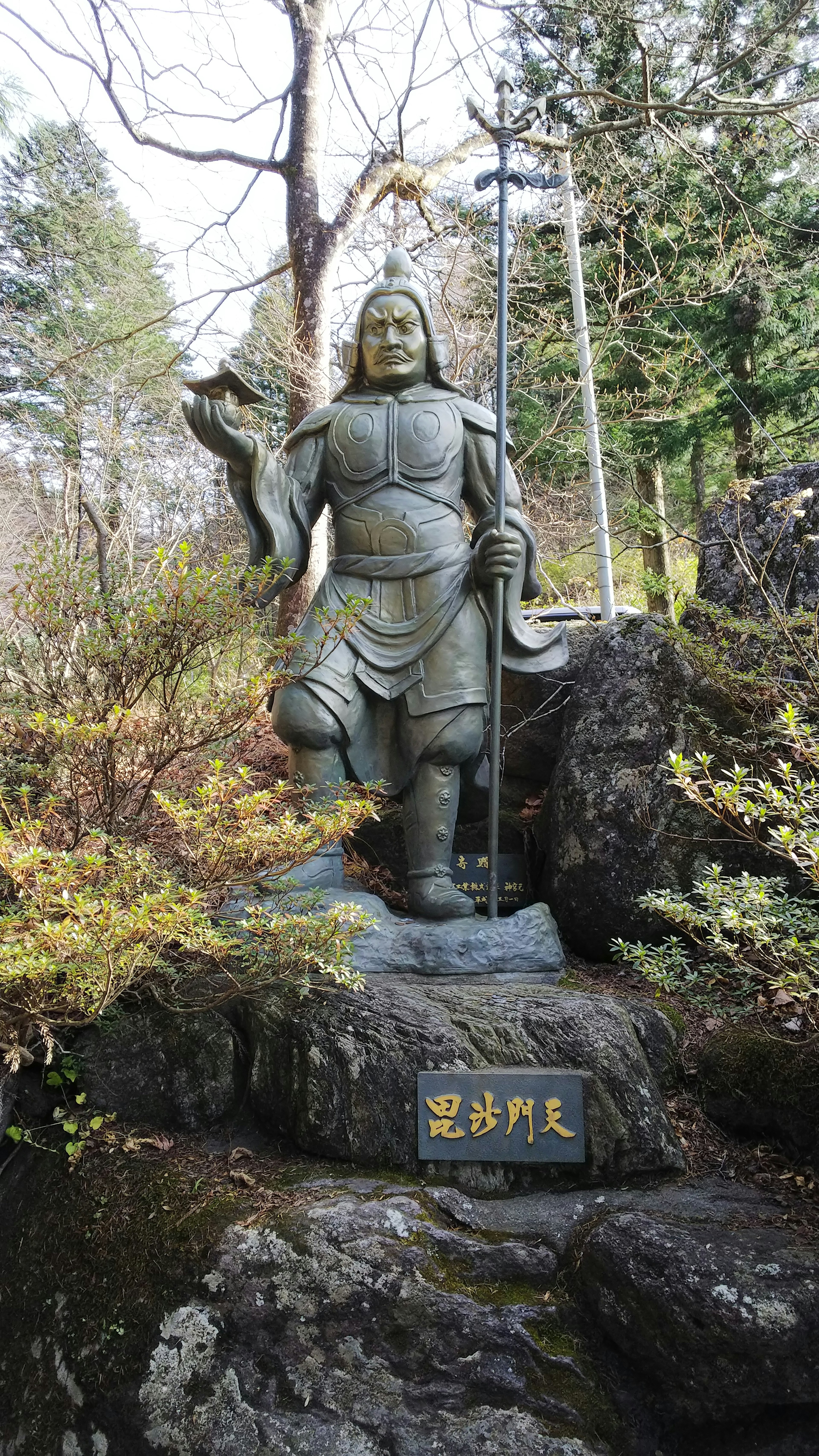 Une statue de guerrier se tenant dans une zone forestière