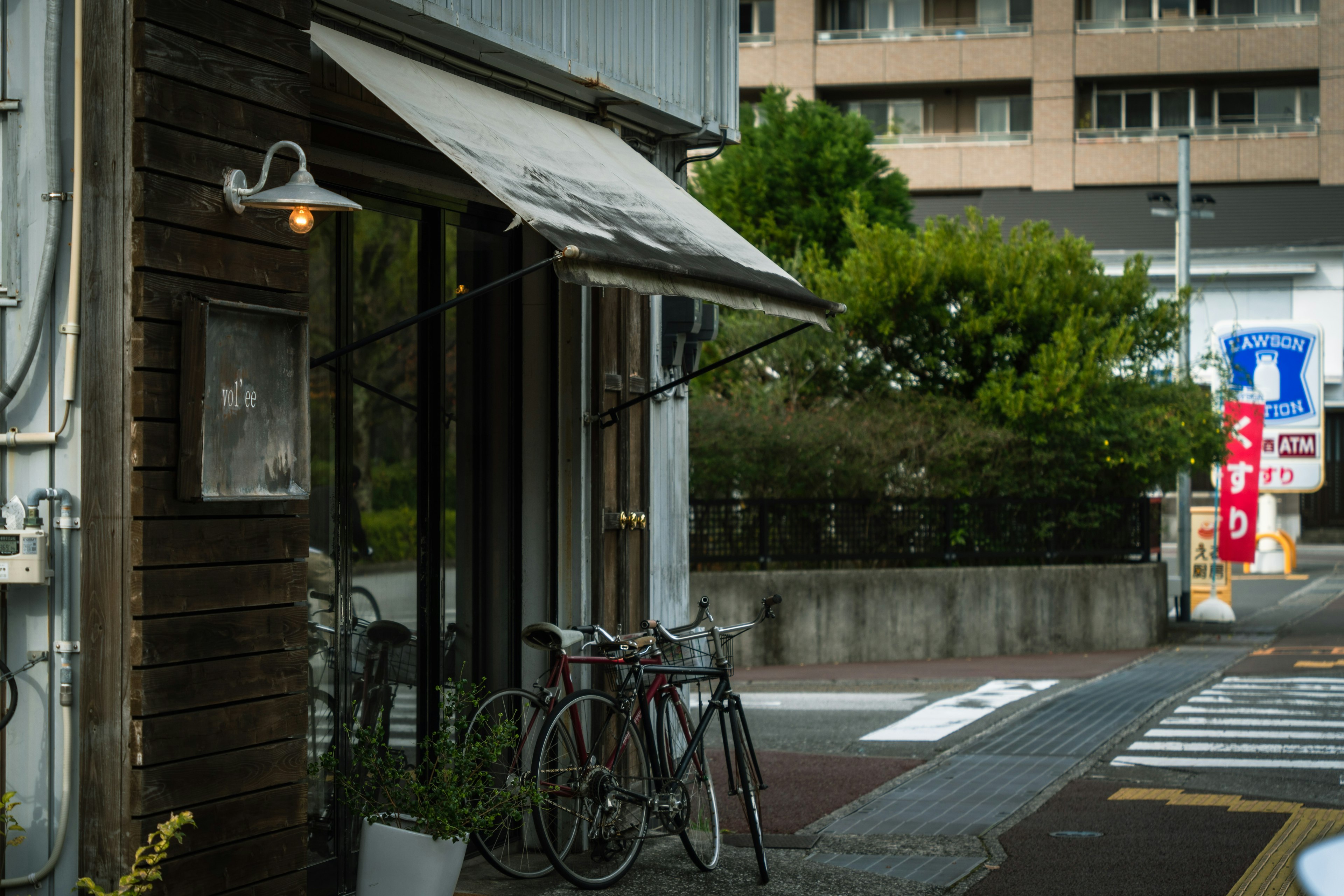 Bicycles parked near a wooden cafe entrance on a green street