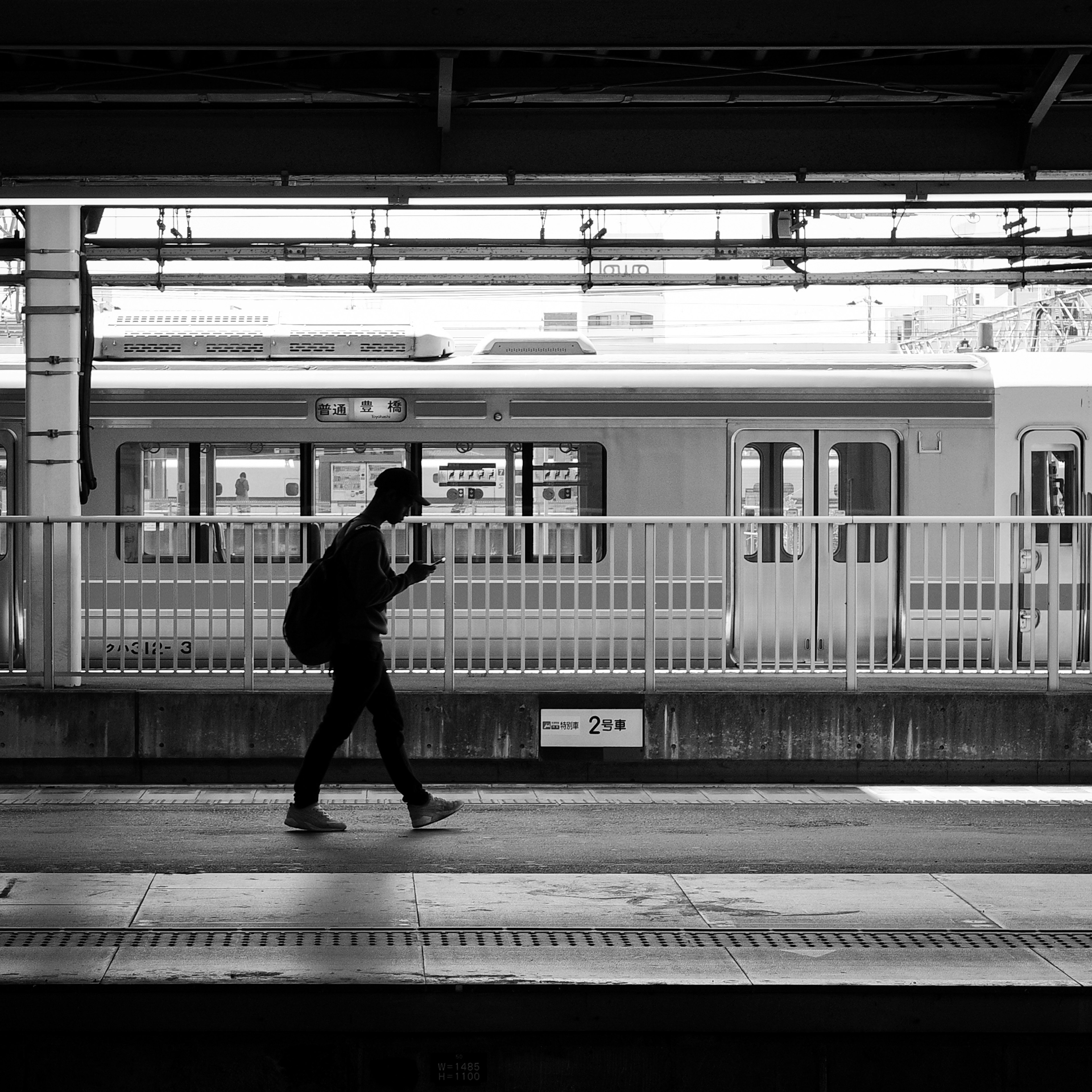 Silhouette einer Person, die an einem Bahnhof mit einem Zug im Hintergrund geht