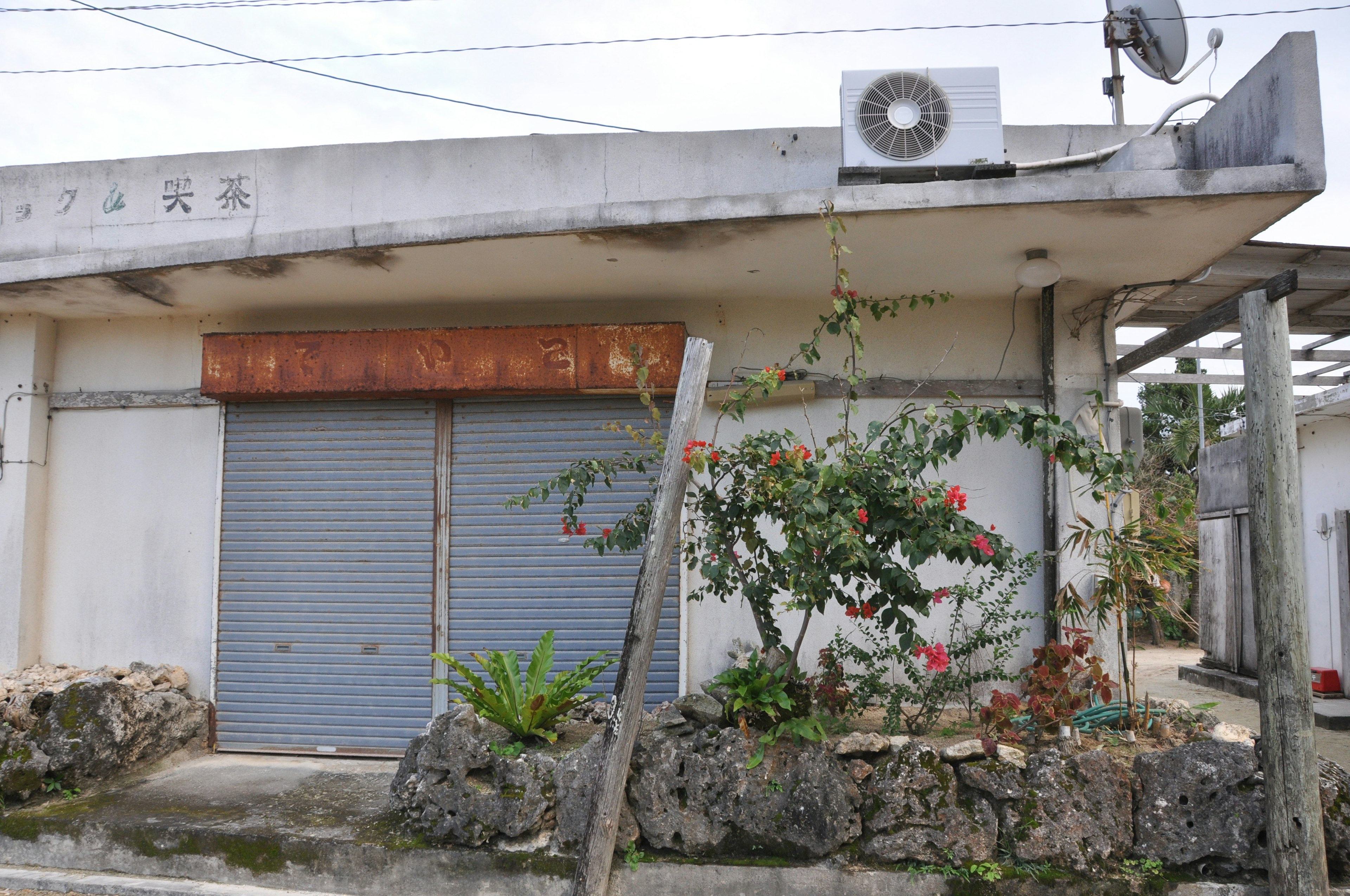 Extérieur d'un vieux magasin avec un climatiseur et une antenne satellite