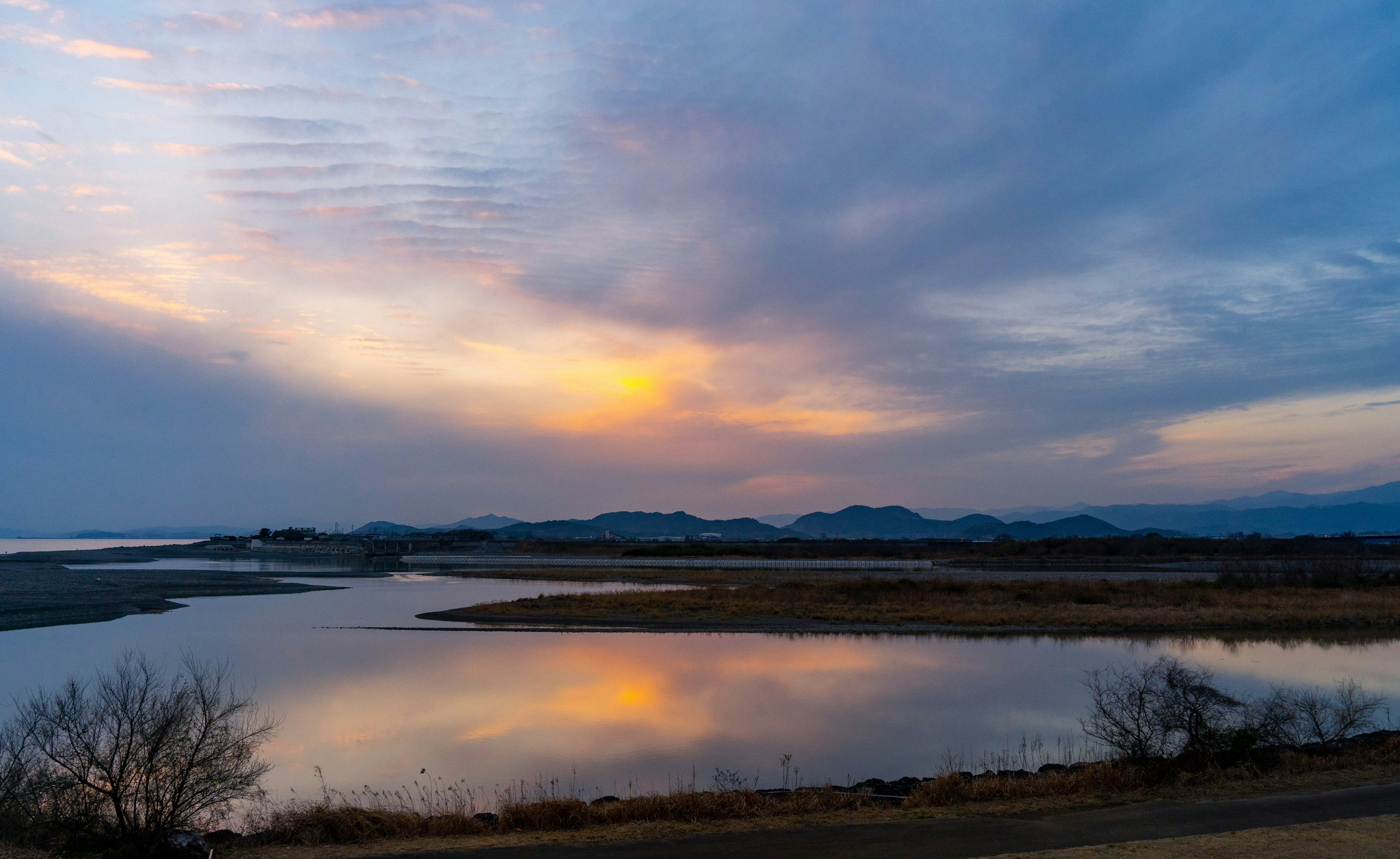 宁静的日落景观，河流倒影，蓝天与橙色太阳，山脉轮廓