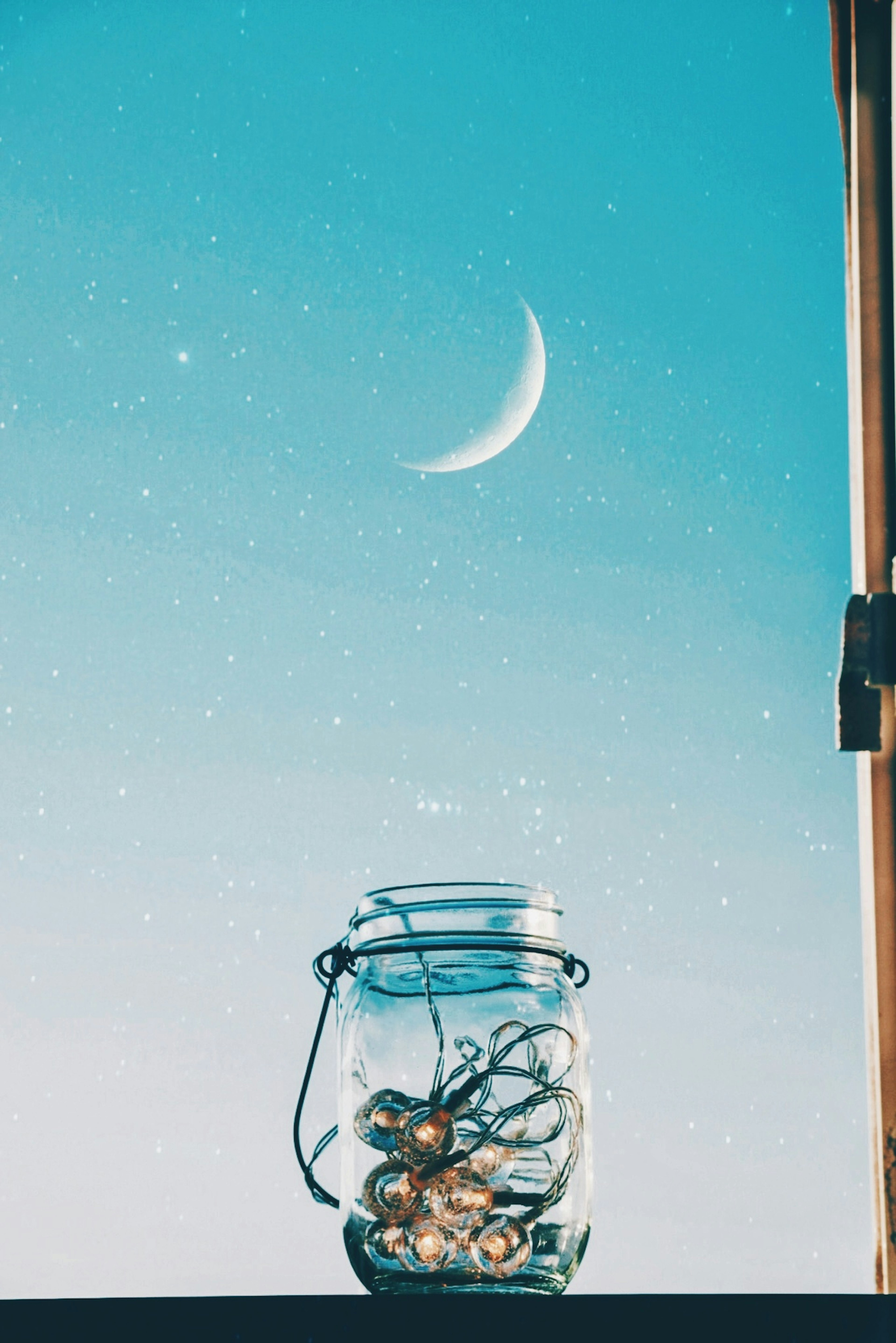 Un bocal en verre rempli d'objets décoratifs avec une lune croissante dans un ciel bleu