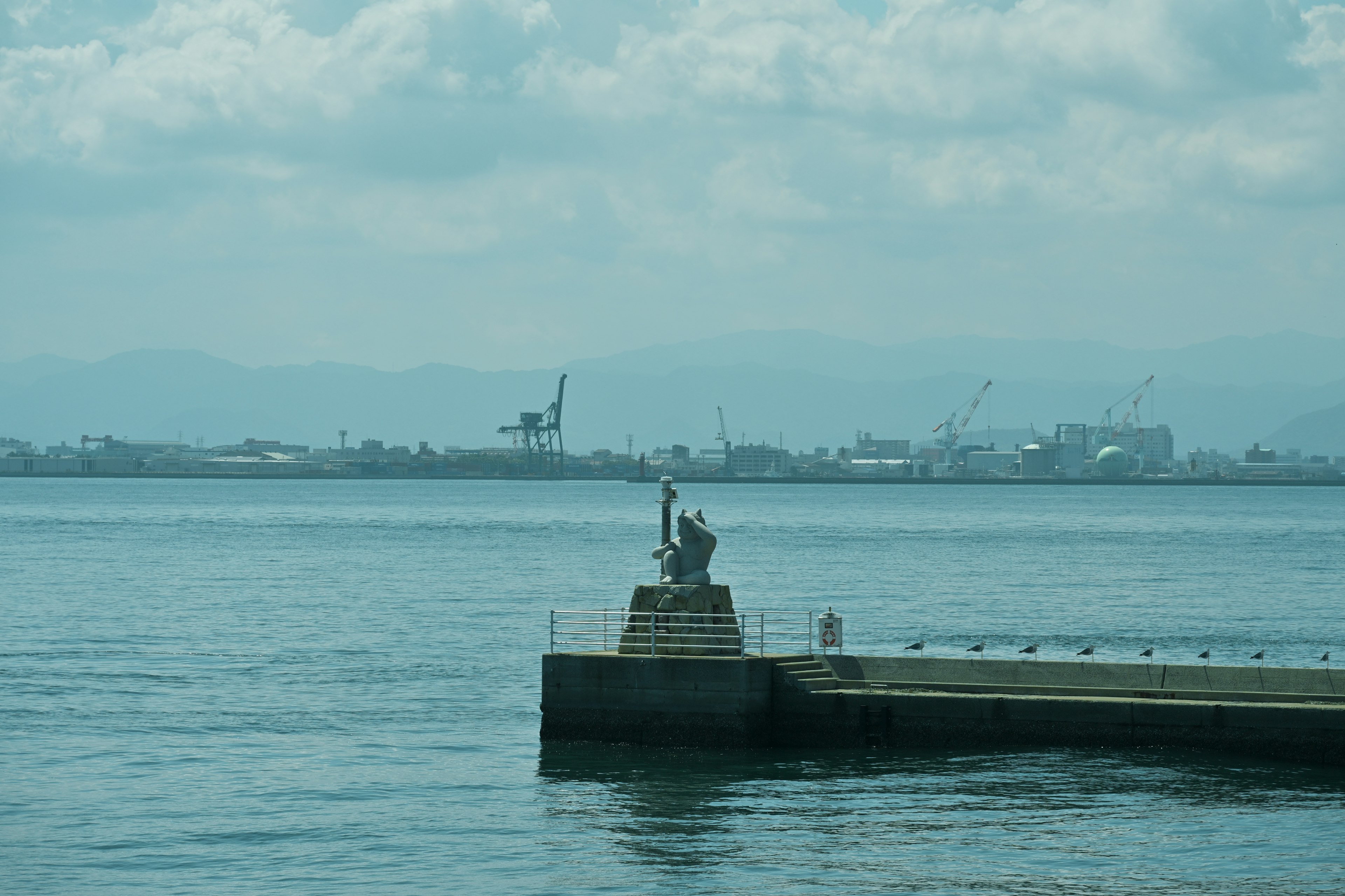 Una vista serena de un muelle con una estatua frente al mar