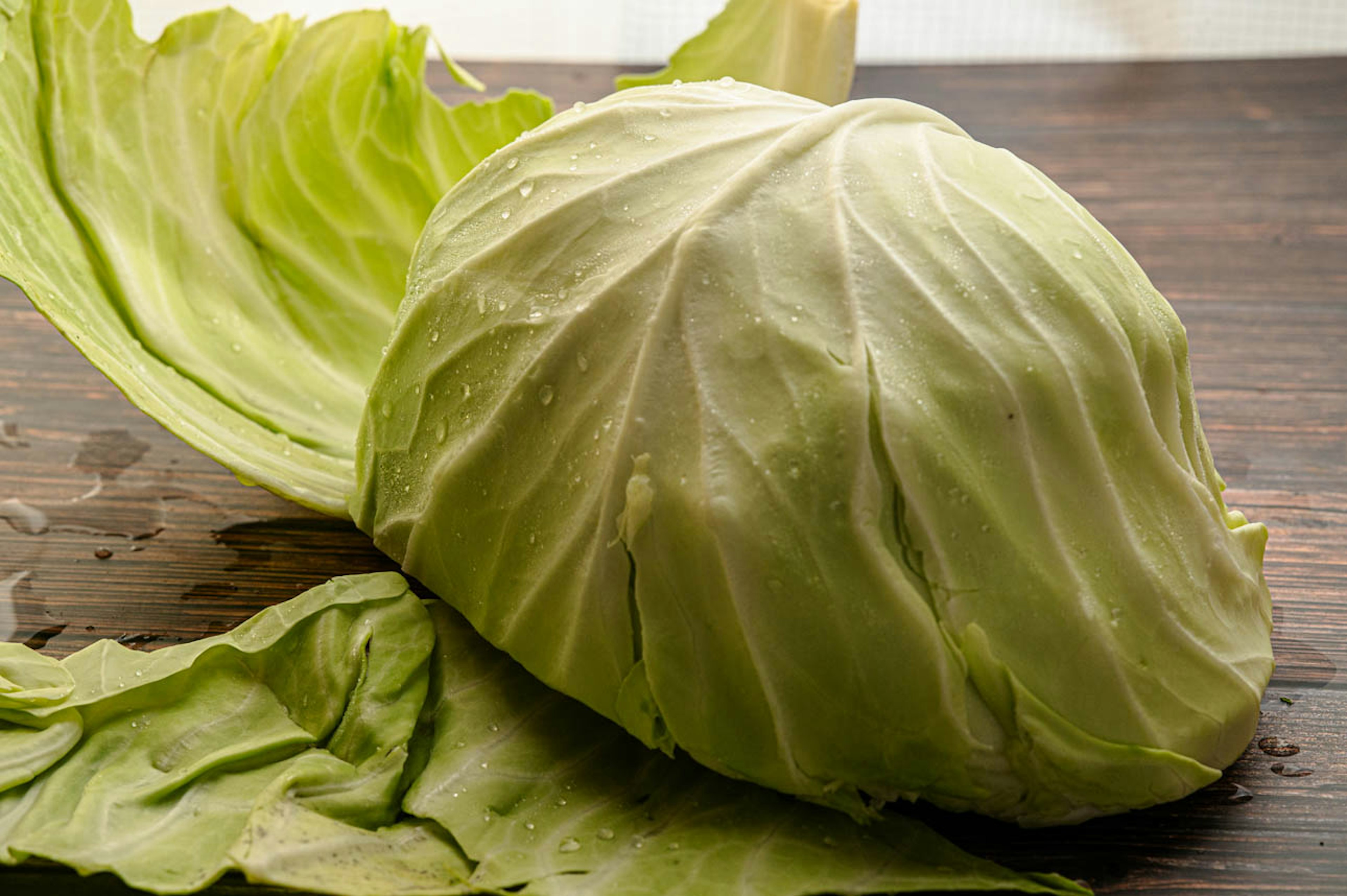 Fresh cabbage with its leaves placed on a wooden table