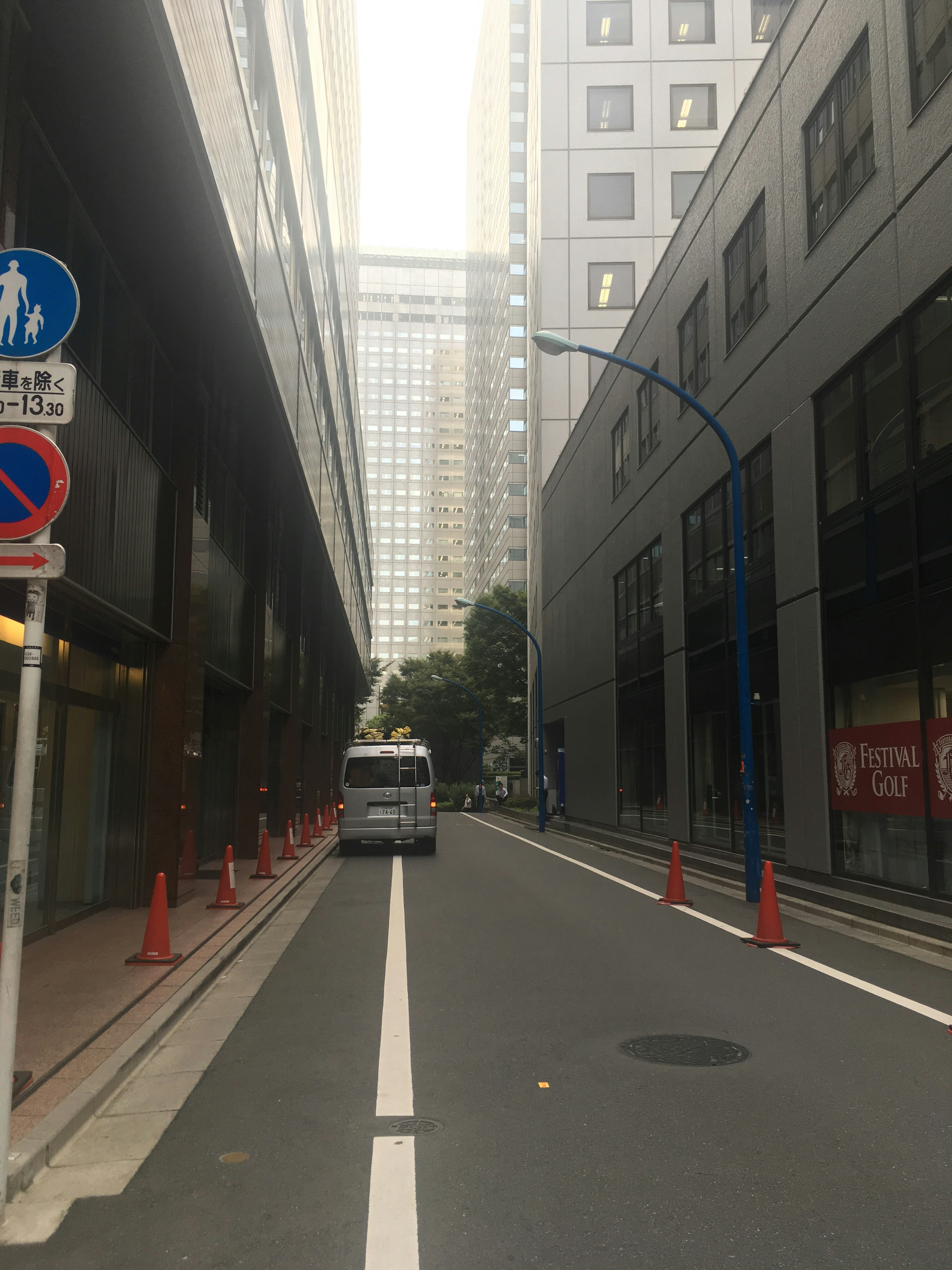 Rue étroite bordée de bâtiments avec une voie blanche et des cônes rouges