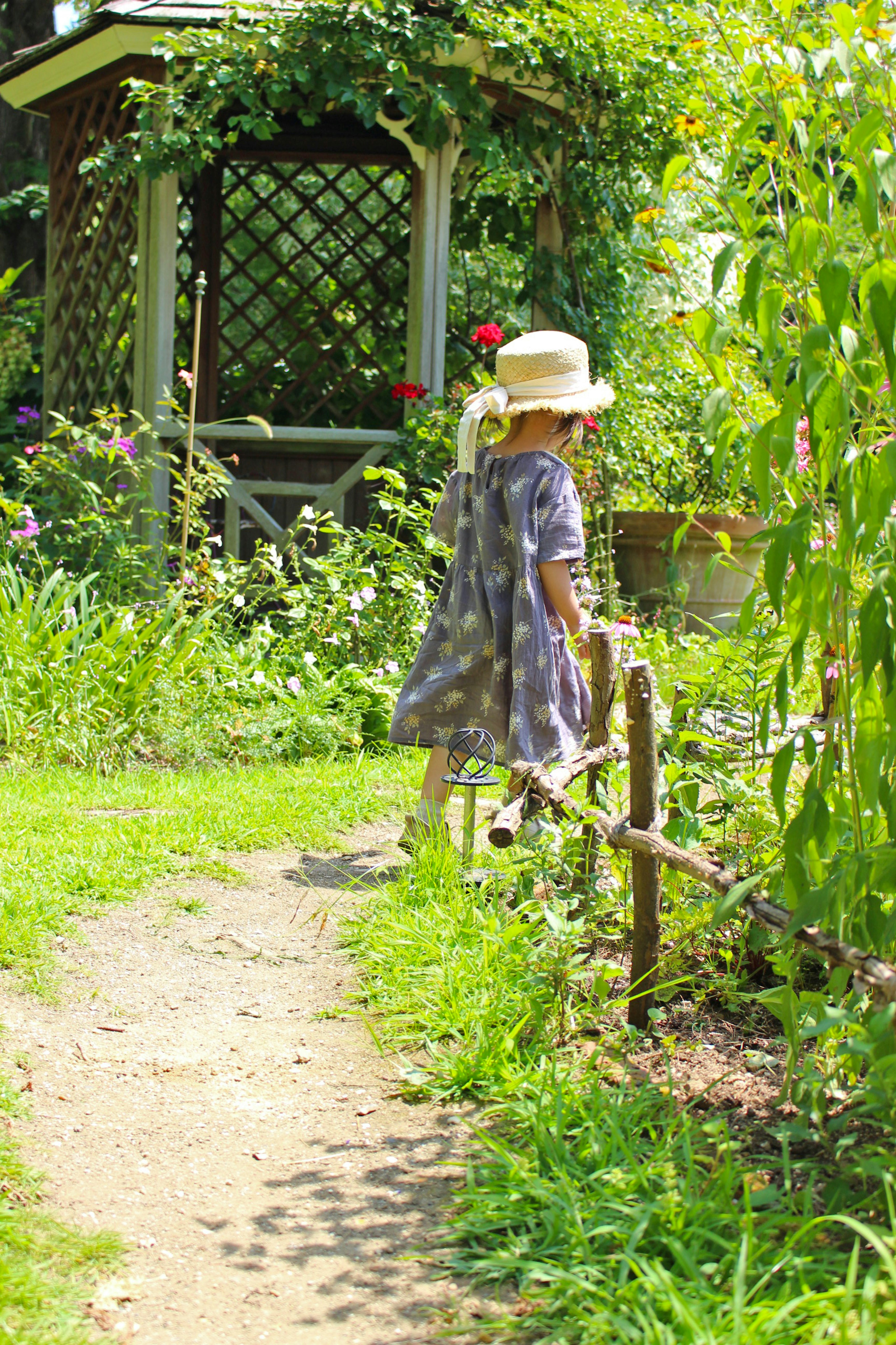 A child walking in a garden surrounded by flowers and greenery a sunny path