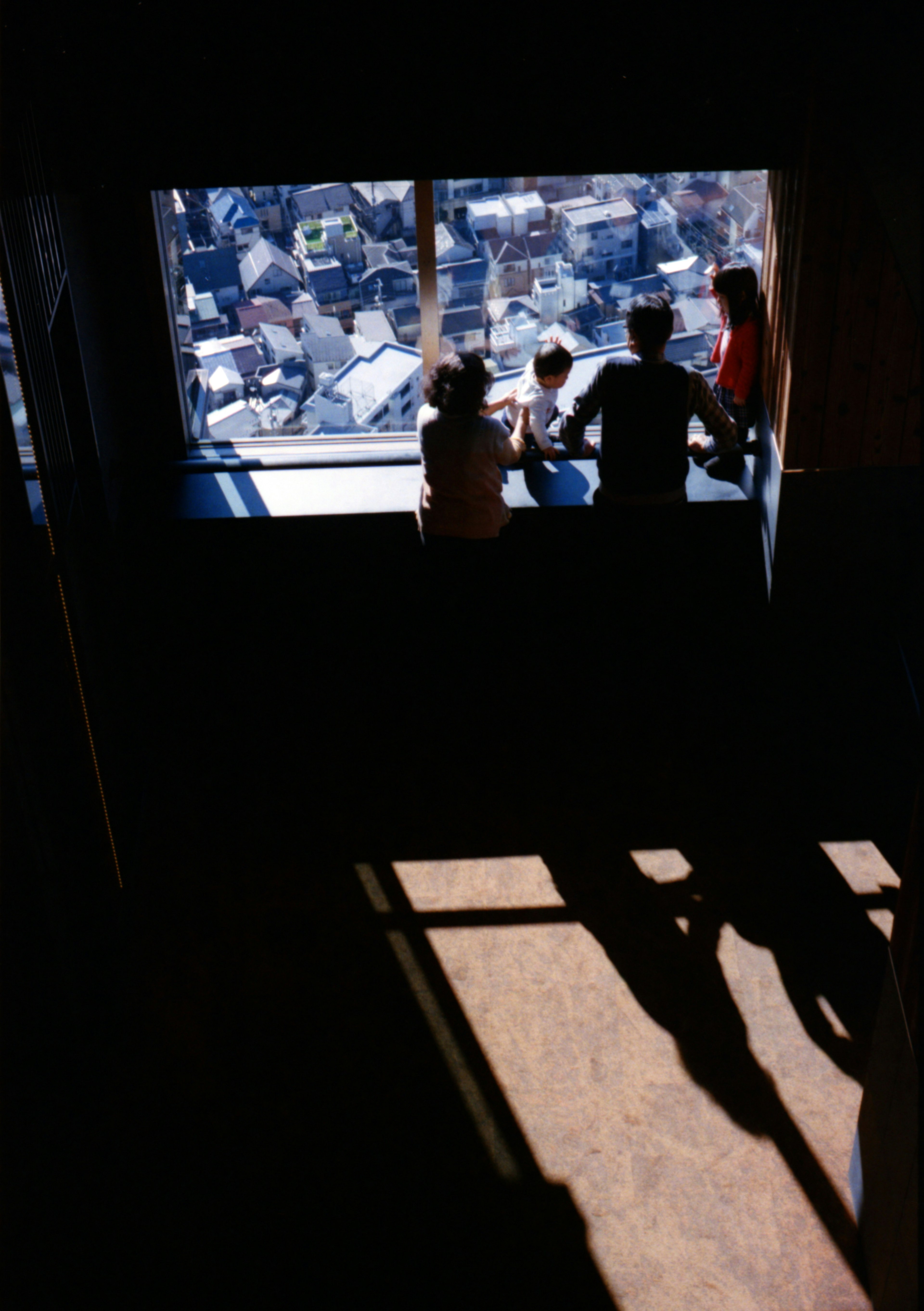 Silhouettes of people talking near a window with a city view