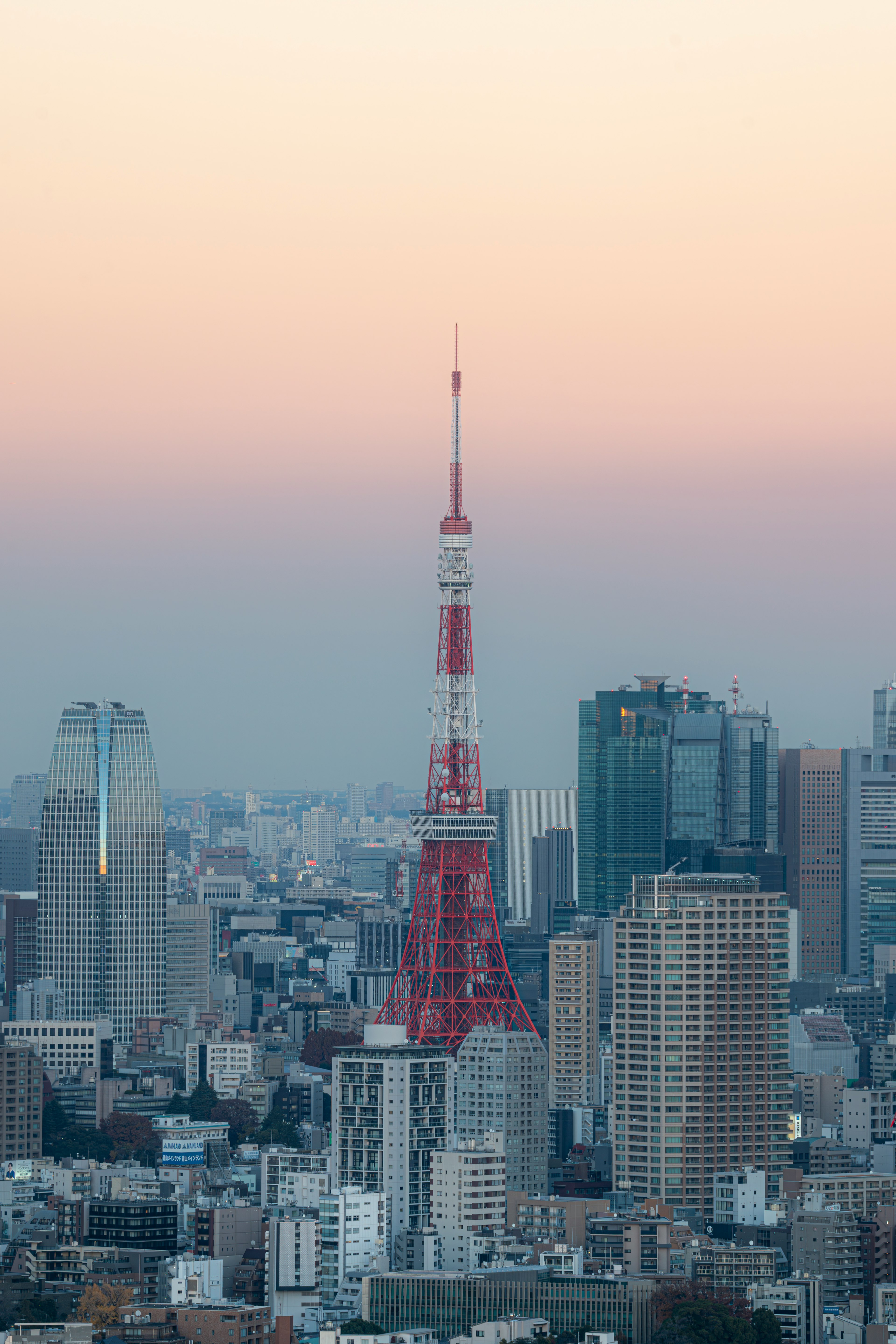 Tokyo Tower stands against a pastel sunset in an urban skyline