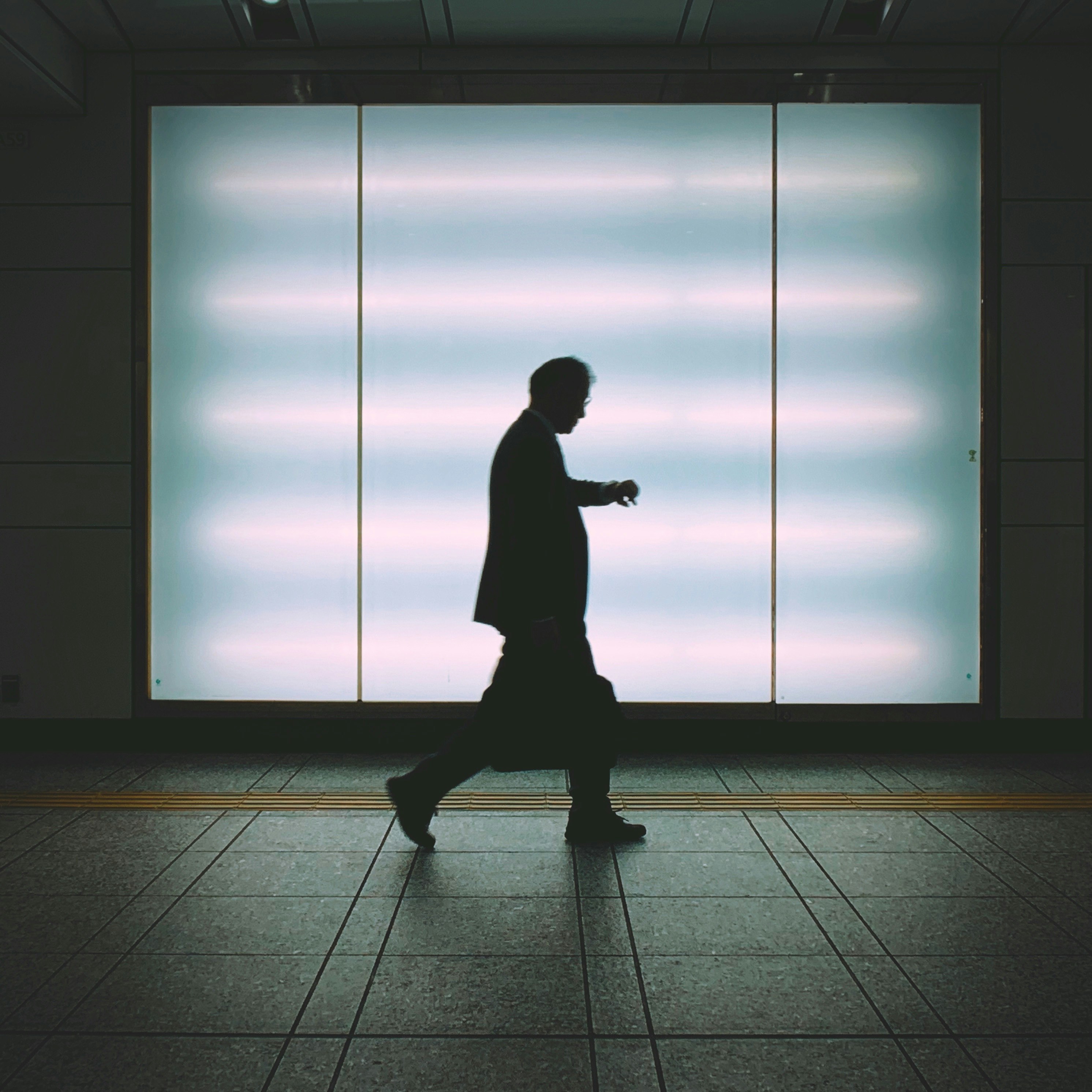 Silhouette of a man walking in front of a bright background