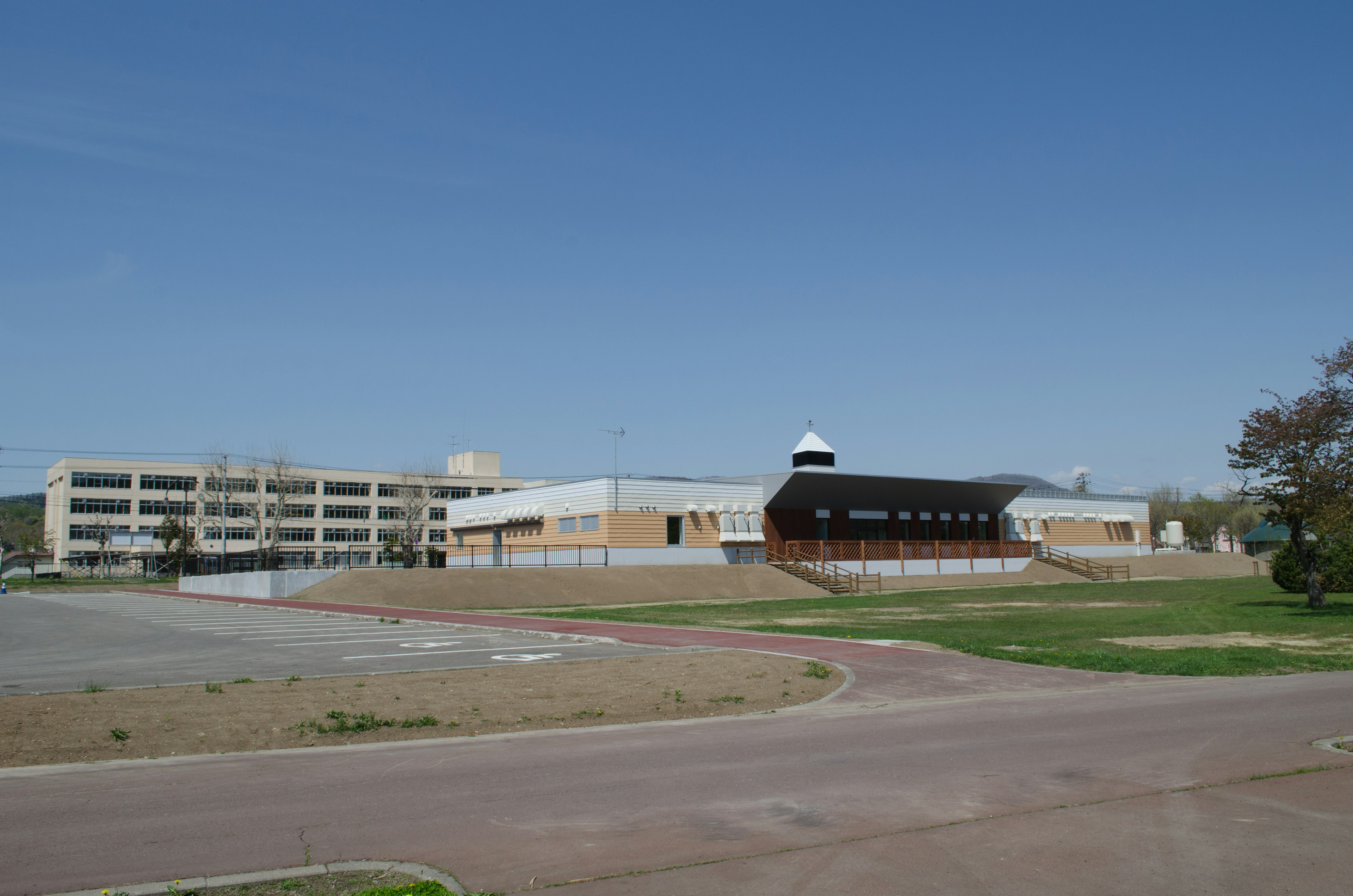 Exterior view of a school with a large parking lot and clear blue sky