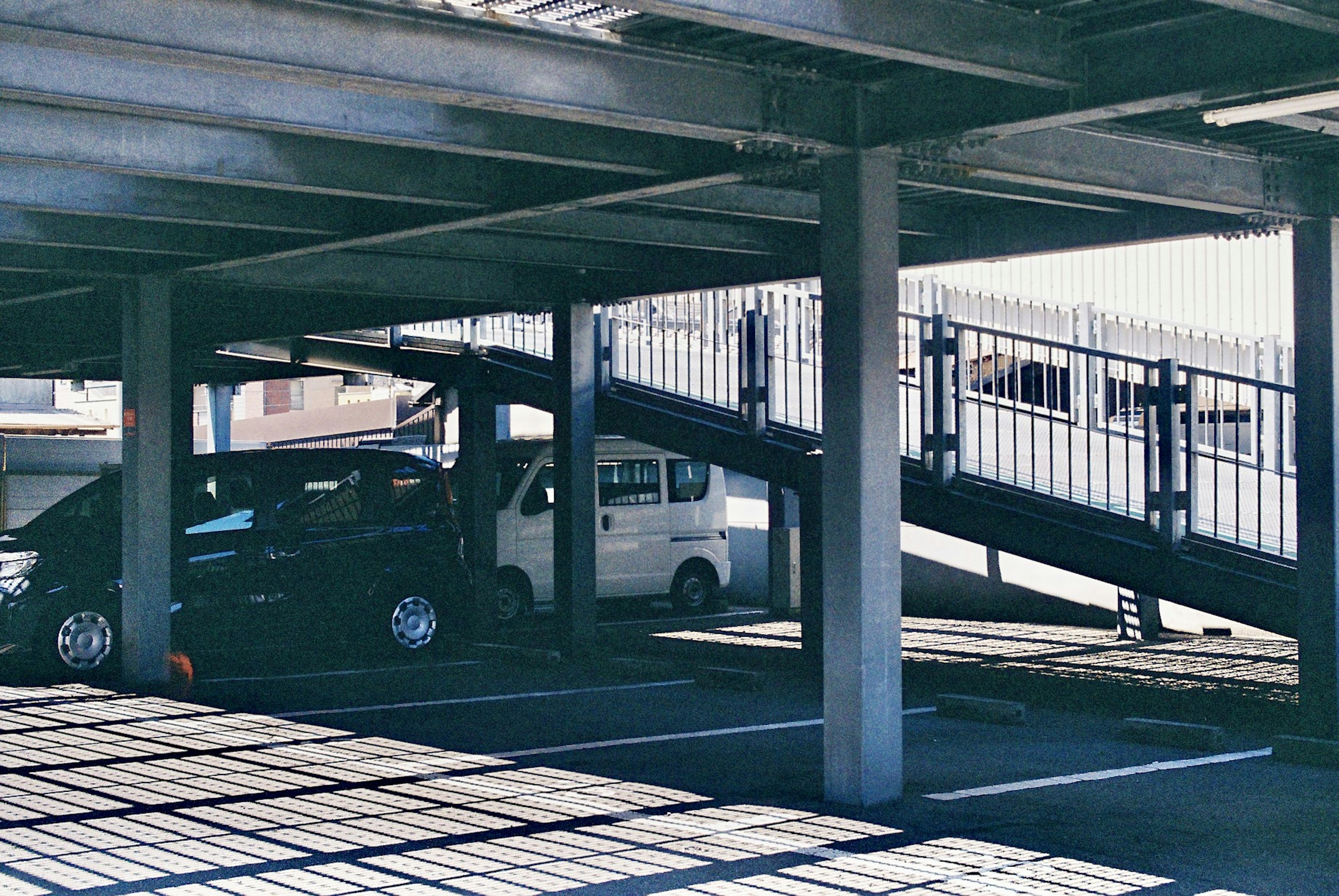 Lower level of a parking garage with parked cars and stairs to the upper level