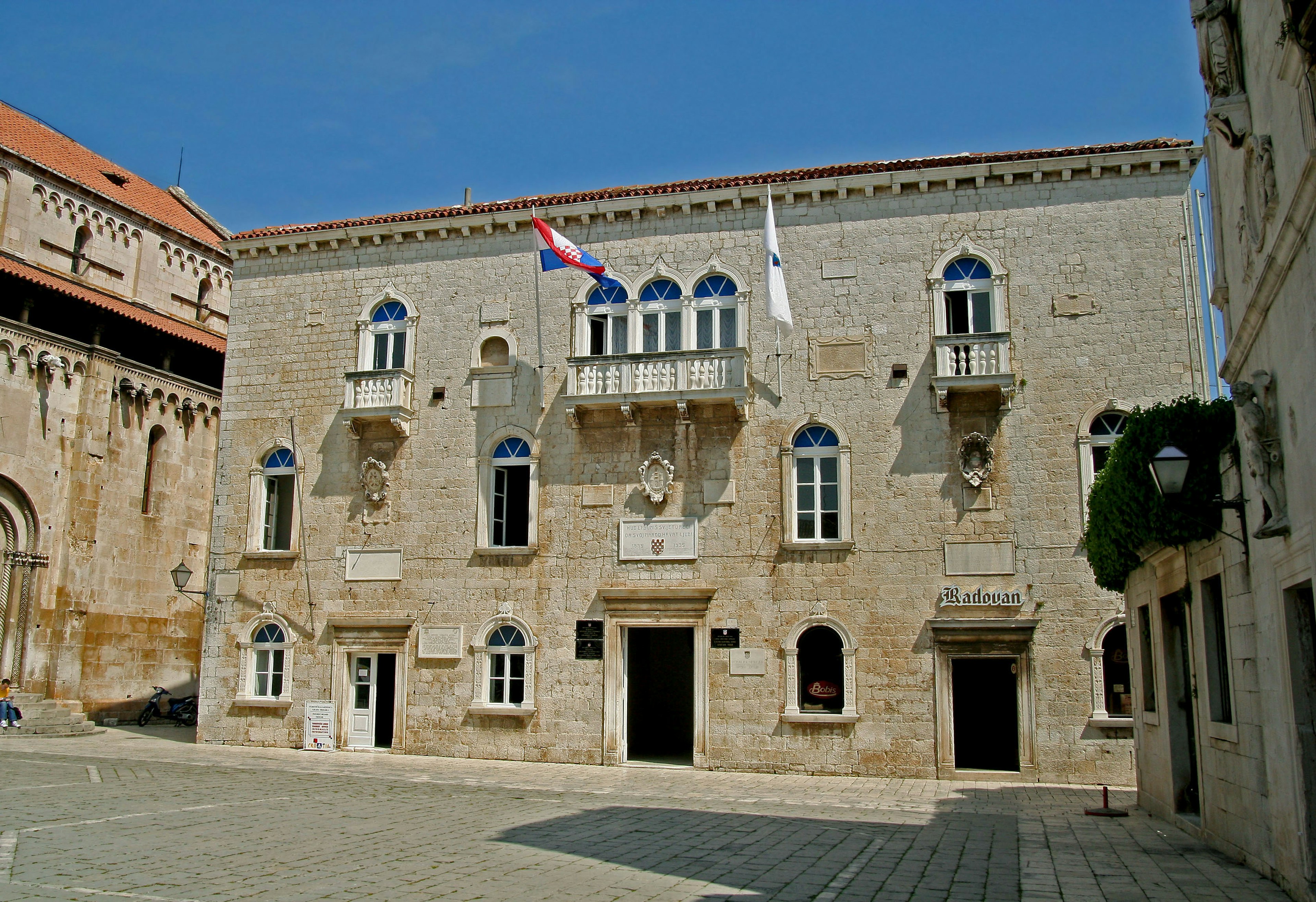 Historisches Steingebäude mit Fenstern und Balkonen unter einem blauen Himmel