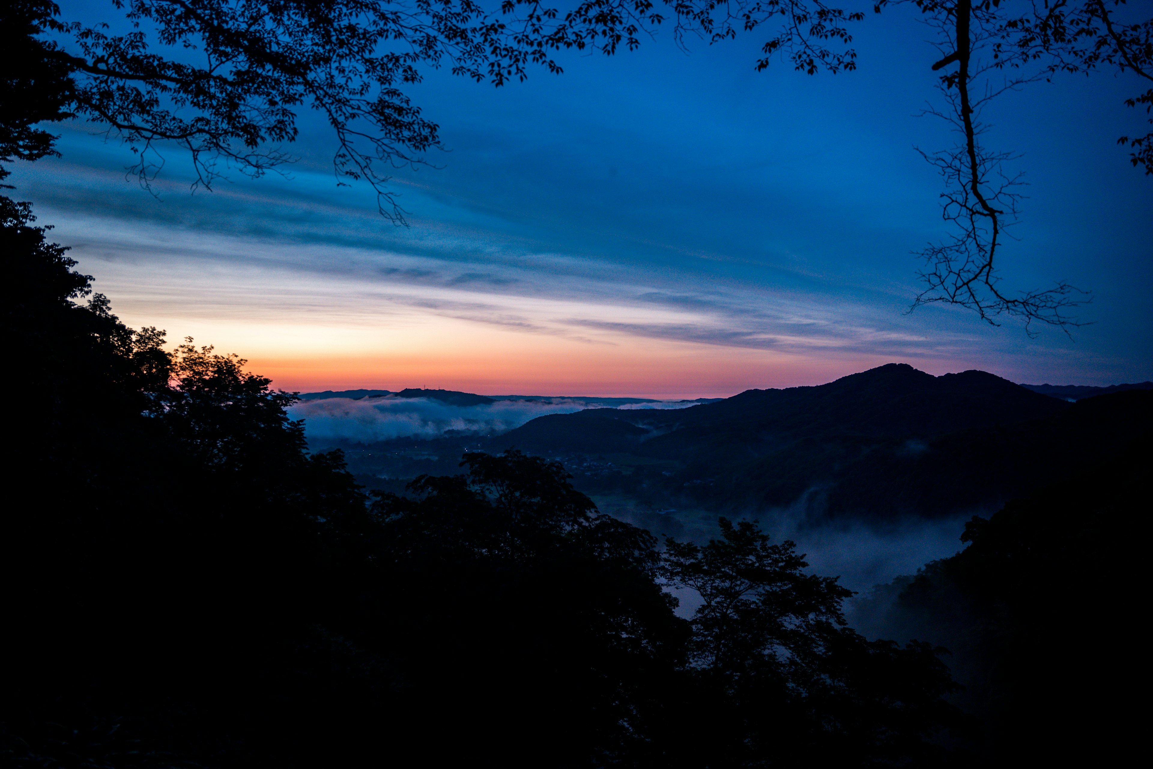 青い空とオレンジ色の夕焼けに包まれた山の風景