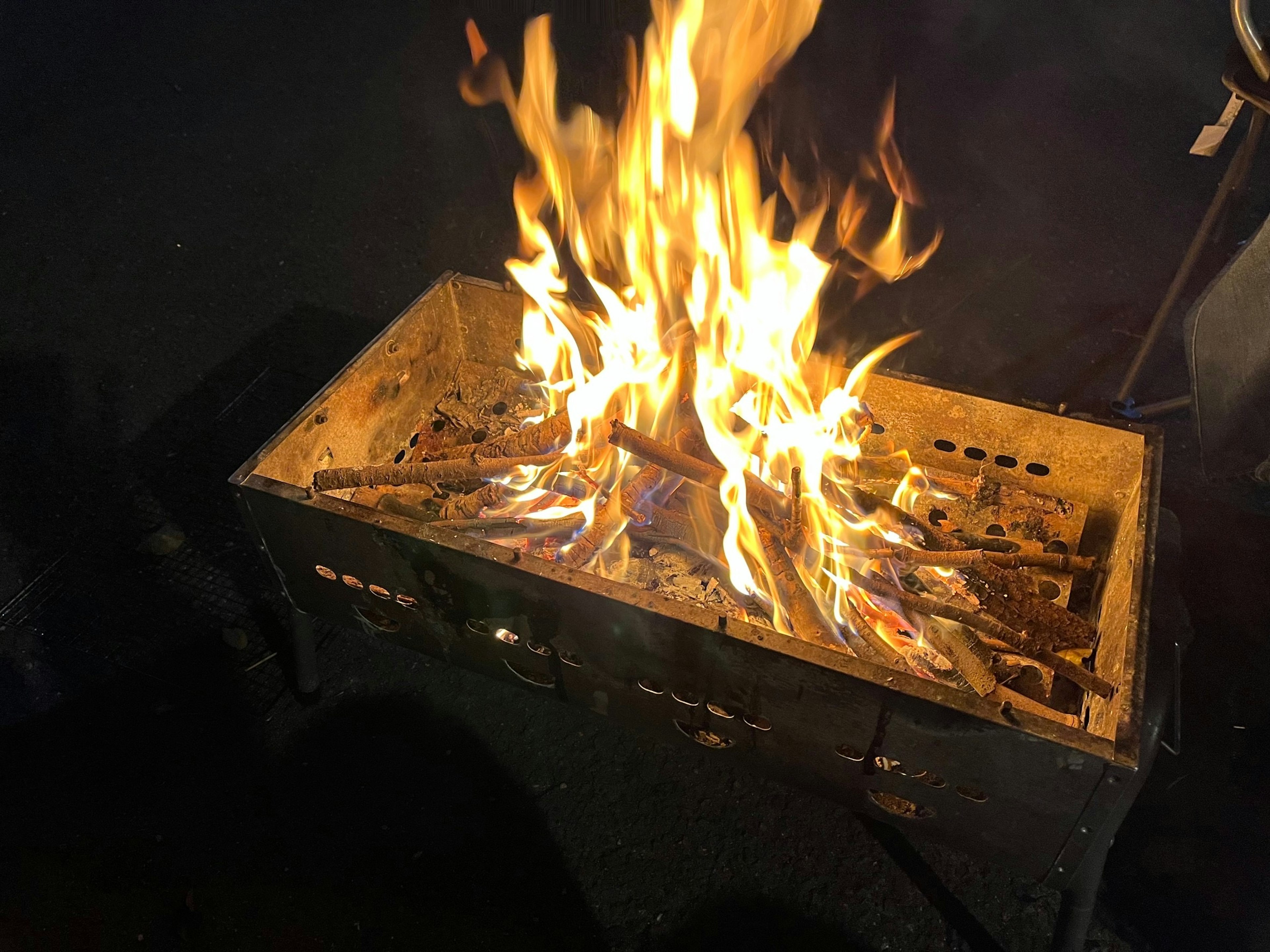 Flammen steigen aus einem Feuerplatz mit Holzscheiten