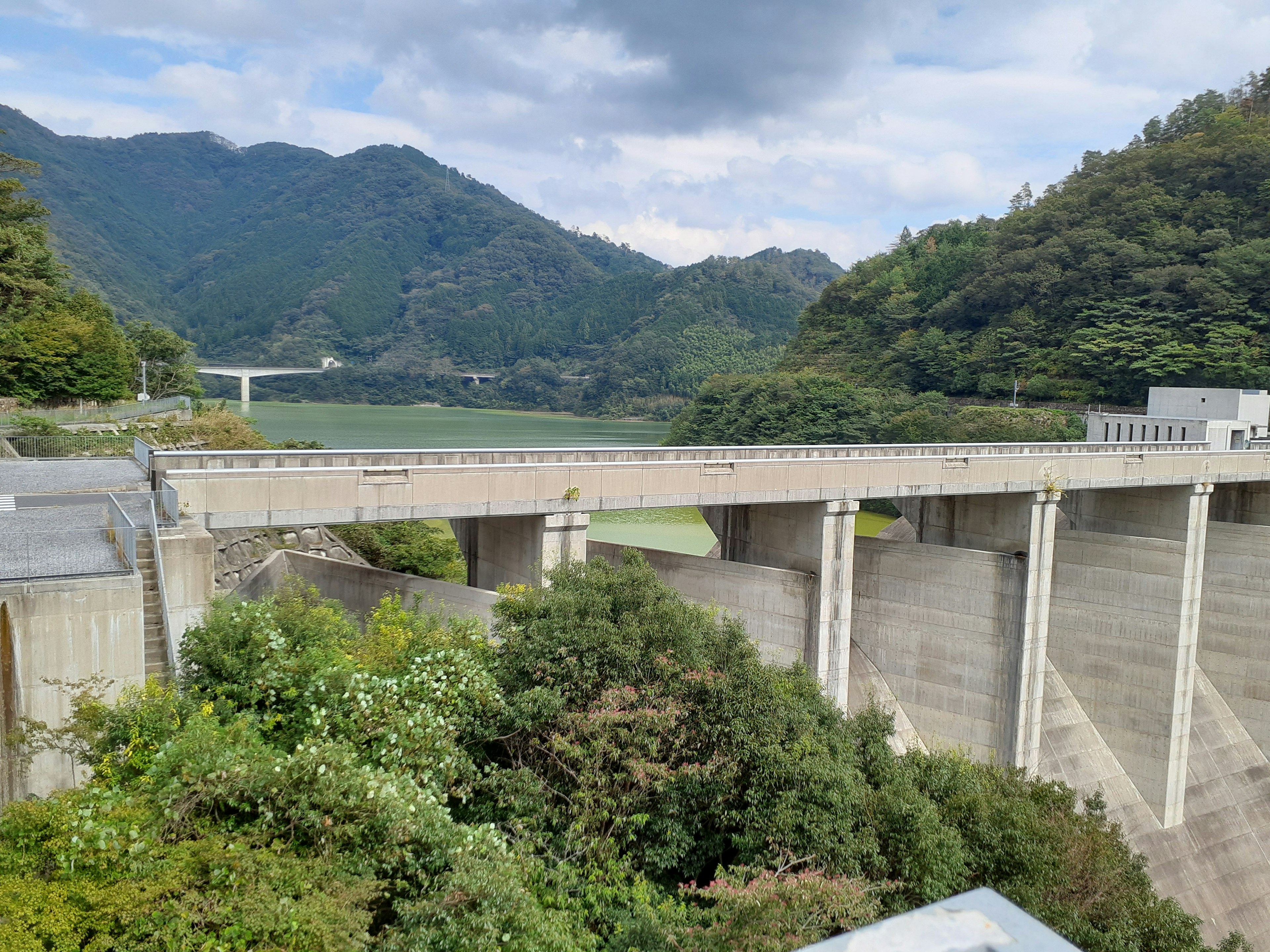 Barrage en béton entouré de montagnes et d'arbres