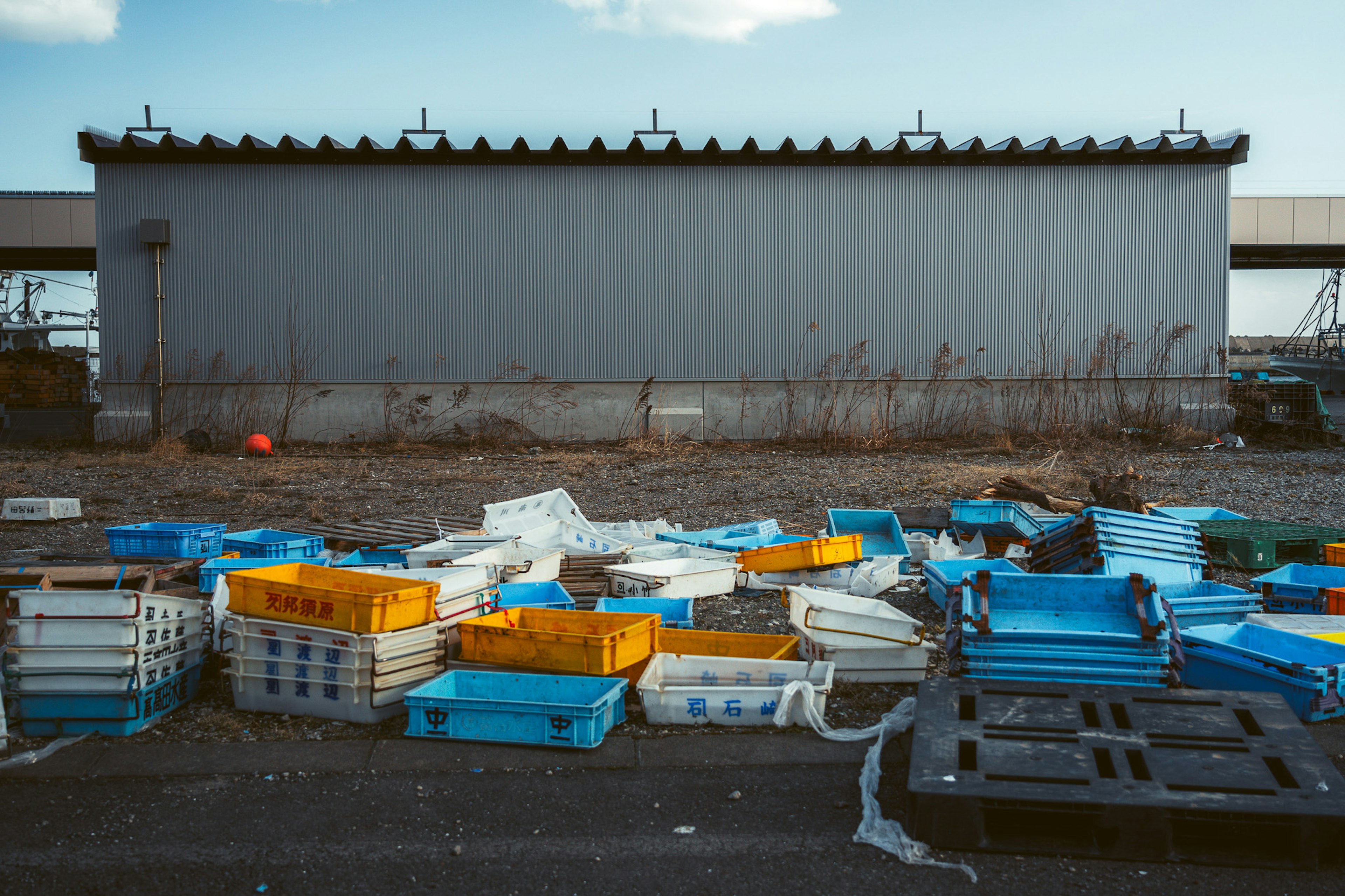 Area industriale con rifiuti e contenitori di plastica gialli e blu sparsi