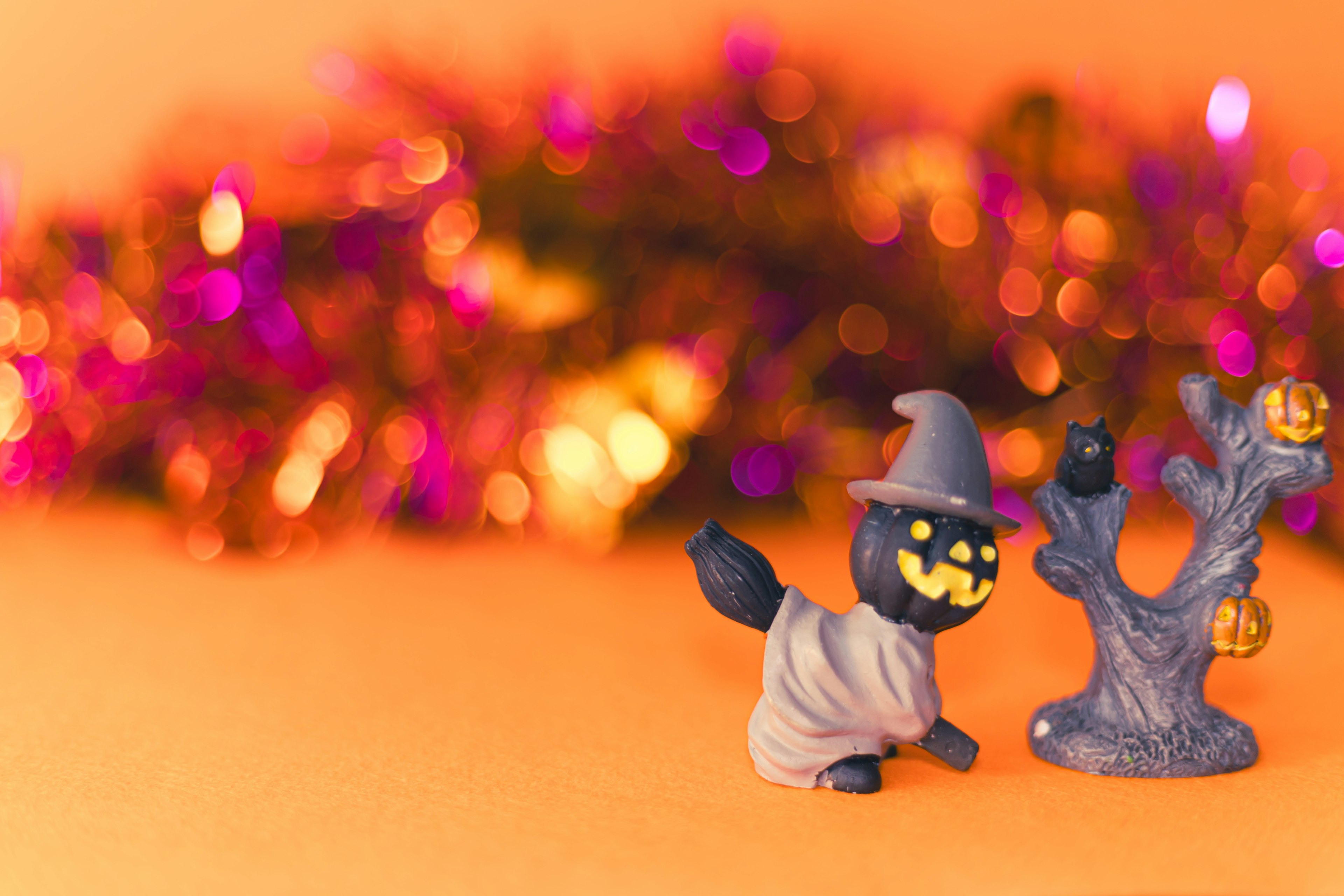 Halloween-themed figurine of a cat in a ghost costume next to a spooky tree decoration