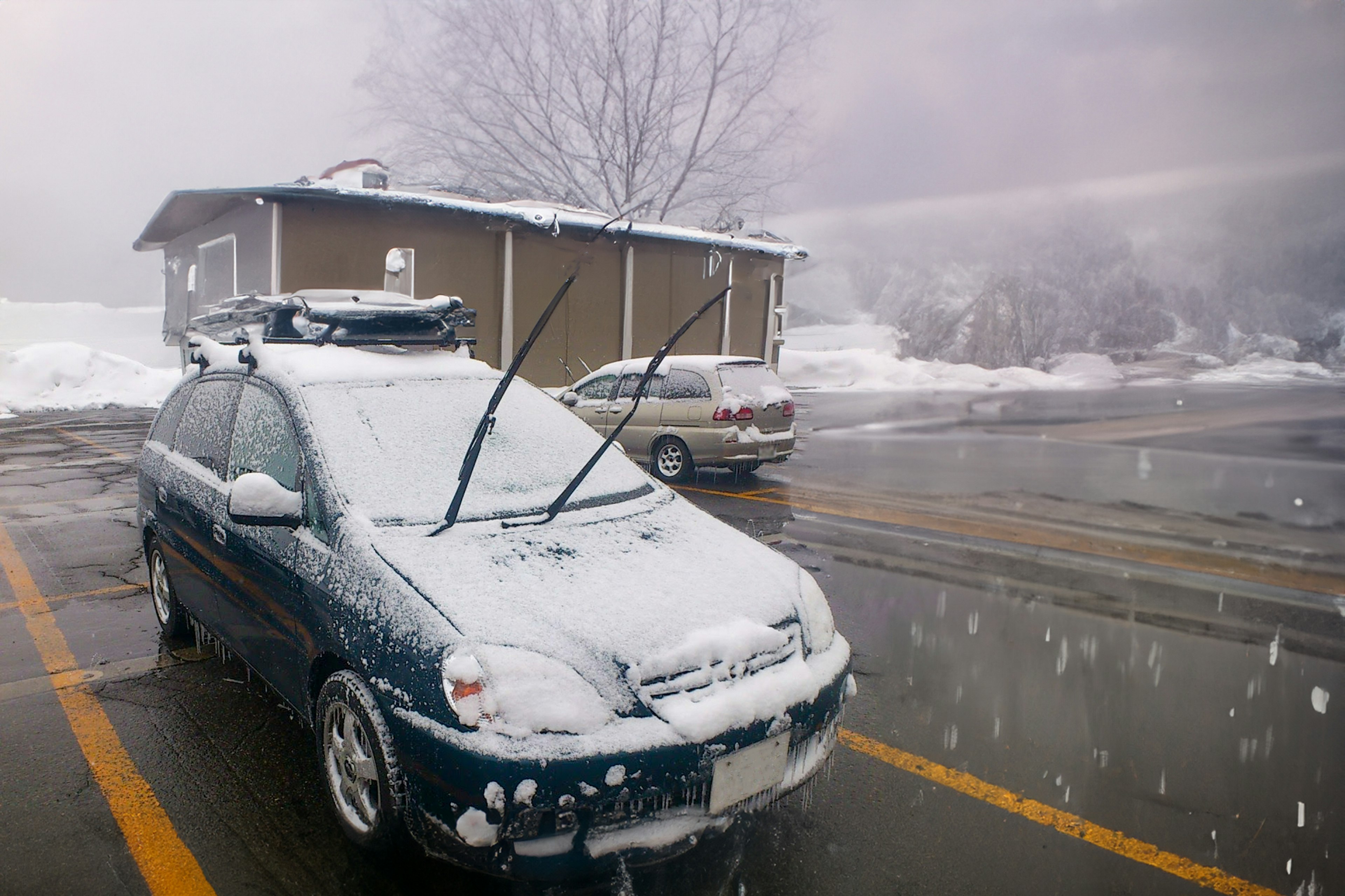 一辆被雪覆盖的车，背景中有飘落的雪花和一栋建筑