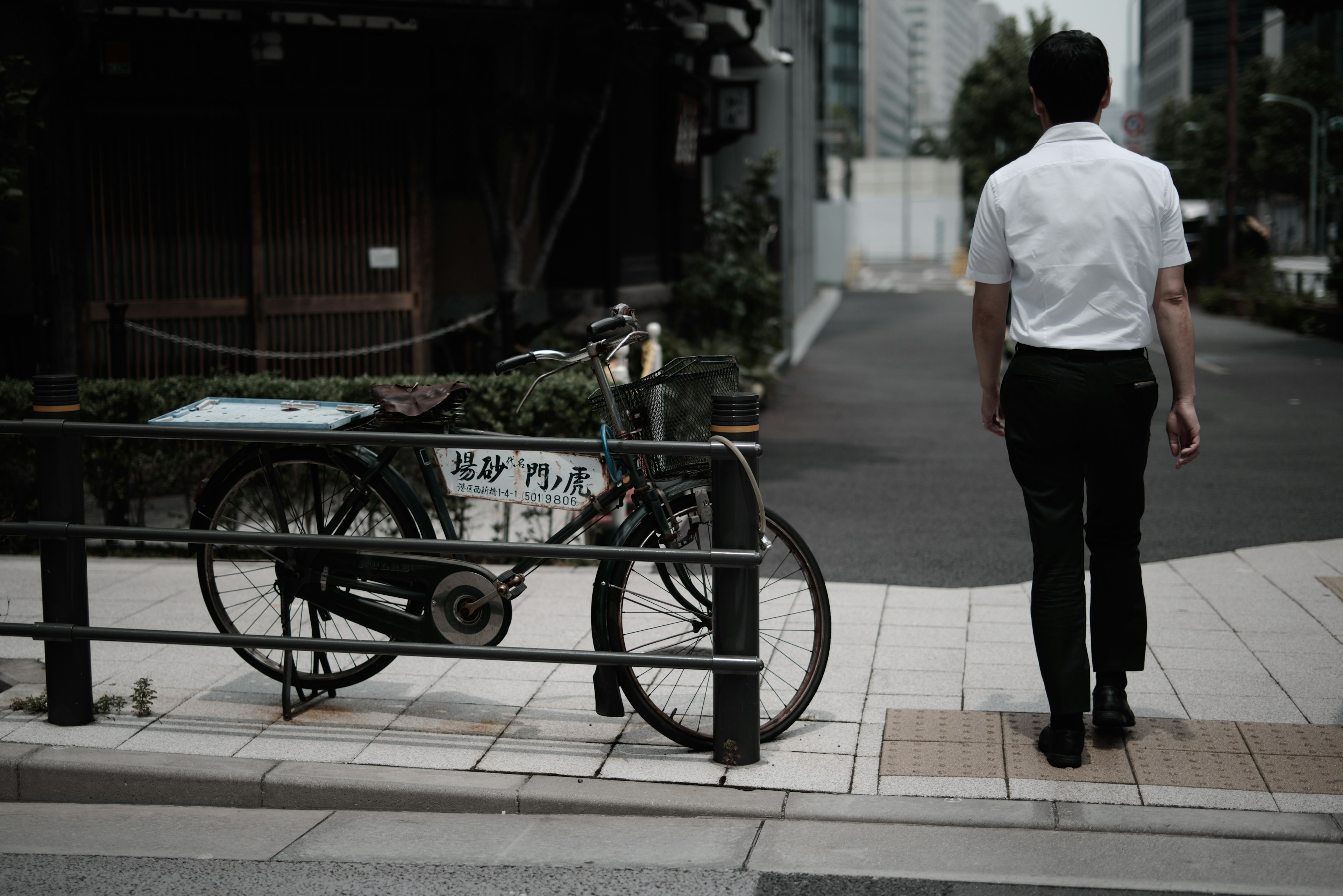 一名穿着白衬衫的男子在城市街道上走过一辆自行车